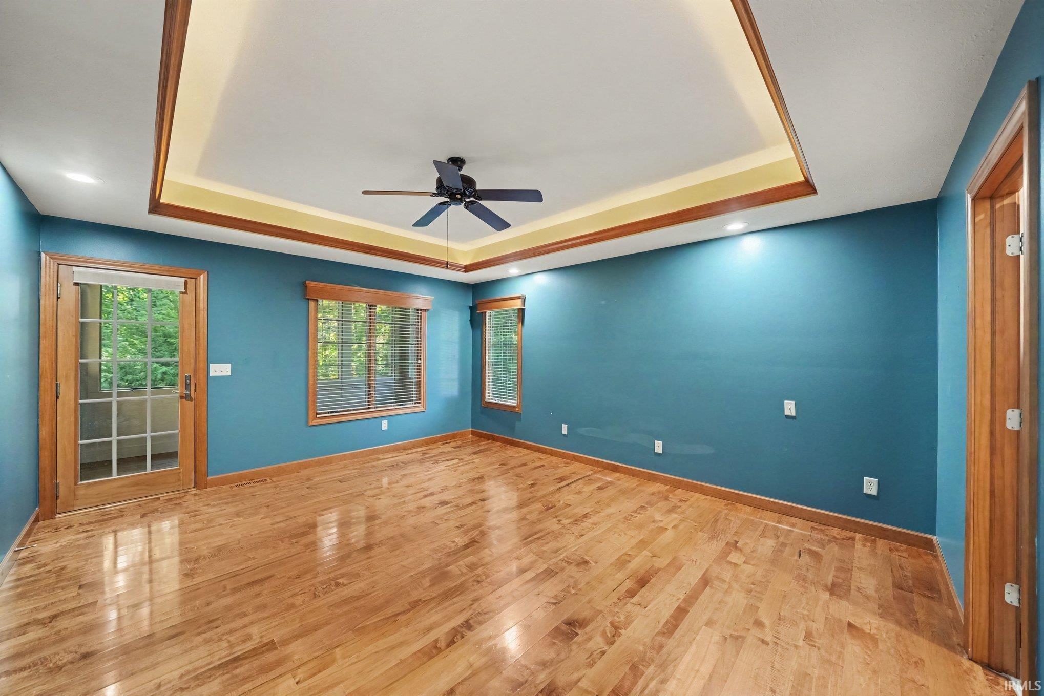 Spacious room featuring wood-finish flooring, a tray ceiling with recessed lighting, a private screened porch