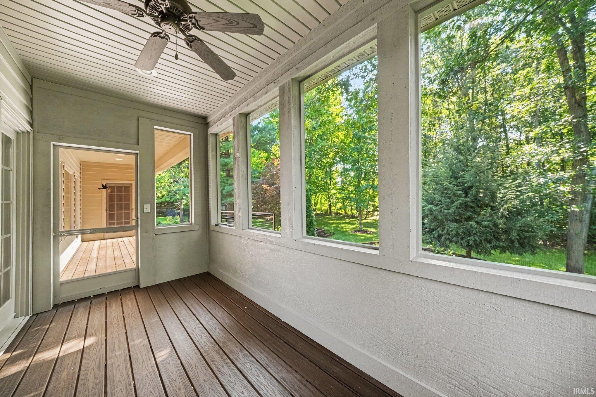 Screened porch with wood-finish flooring and a ceiling fan
