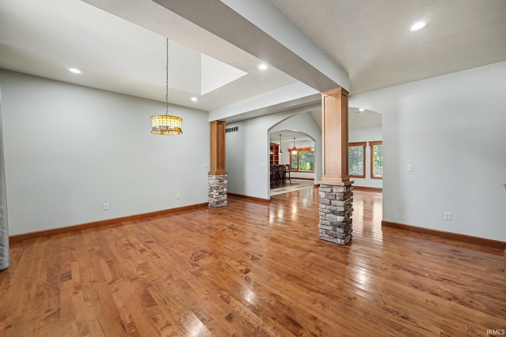 Open entry to Dining with columns, recessed lighting, and a decorative chandelier