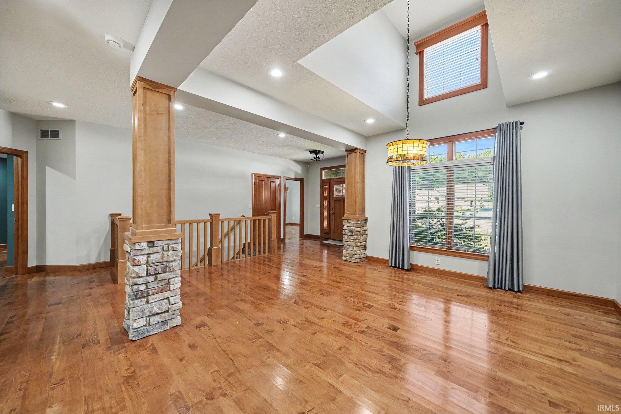 Spacious open-concept dining room showcasing vaulted ceilings, hardwood flooring