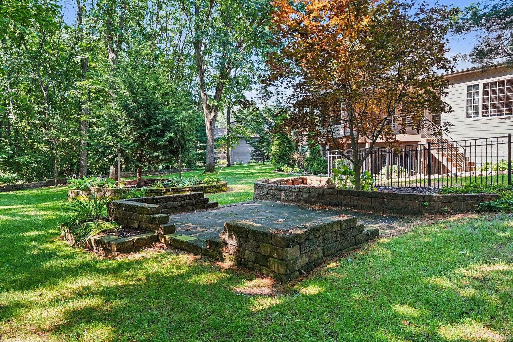 Mature landscaping defines this expansive backyard oasis, featuring mature deciduous and evergreen trees providing natural shade, manicured lawn, and secure fencing