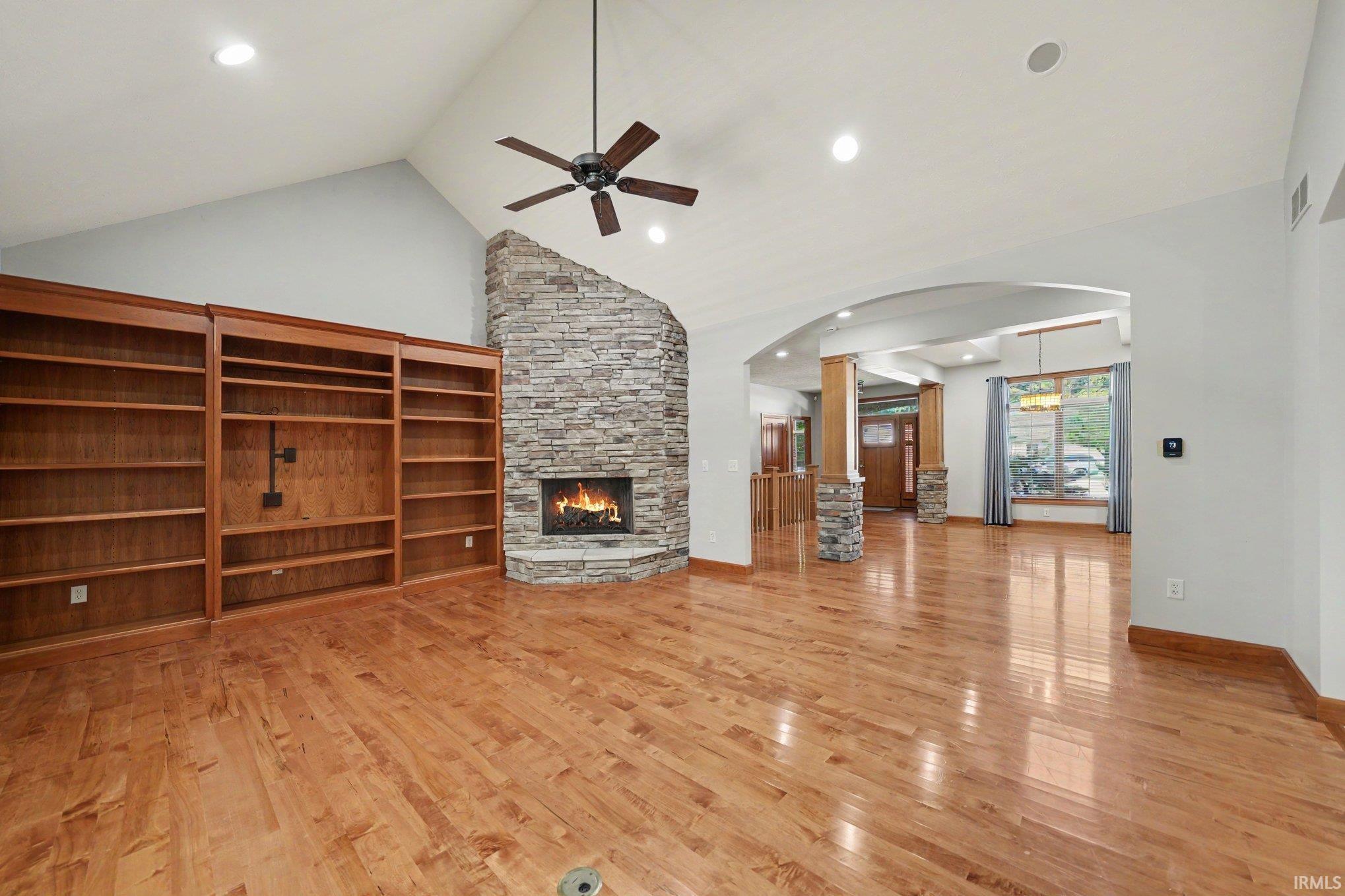 Spacious room featuring wood-finish flooring, a stone Gas fireplace, and vaulted ceilings with recessed lighting