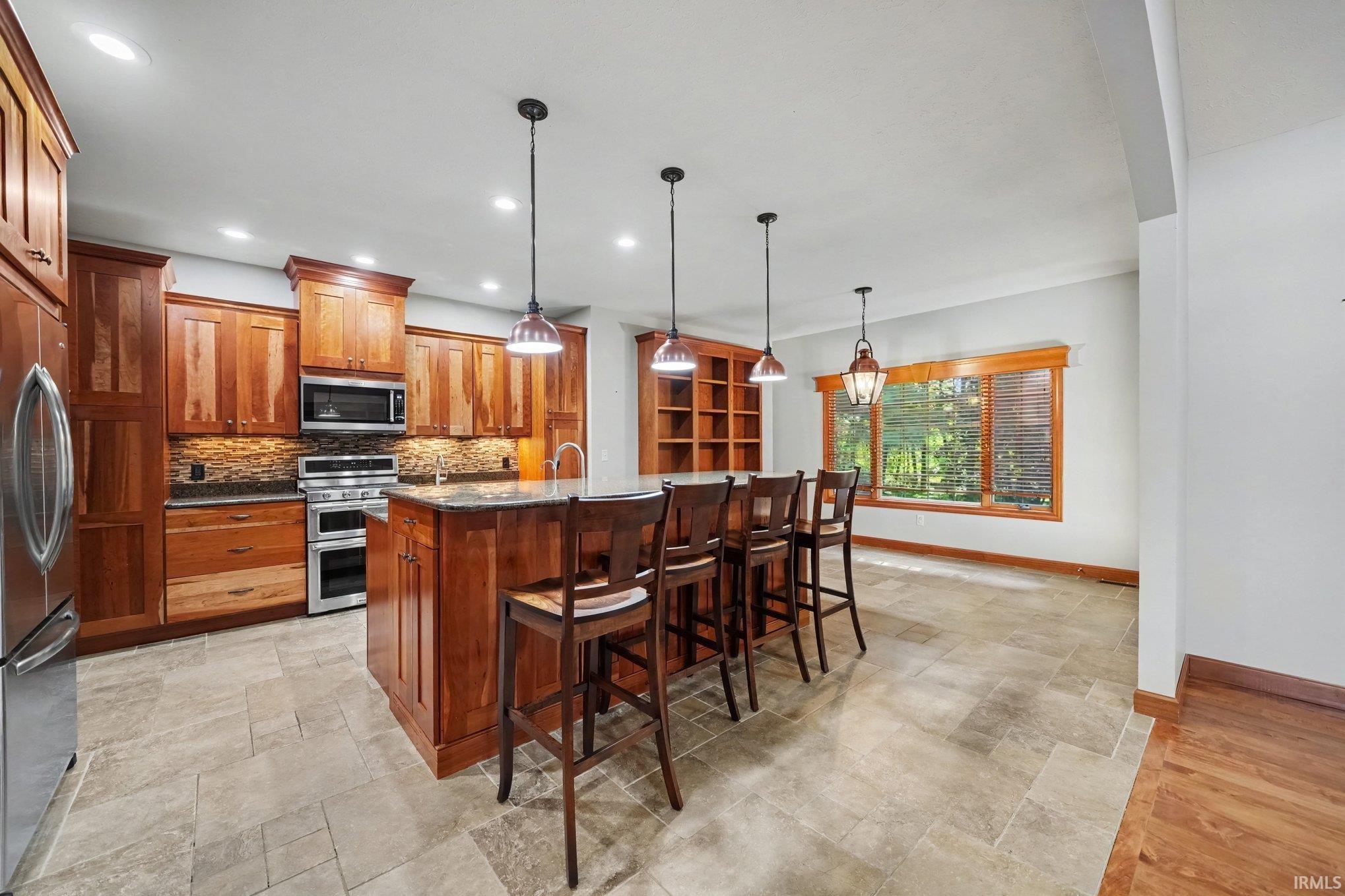 Gourmet kitchen featuring rich wood cabinetry, stainless steel appliances, granite countertops, and a large center island with seating for four