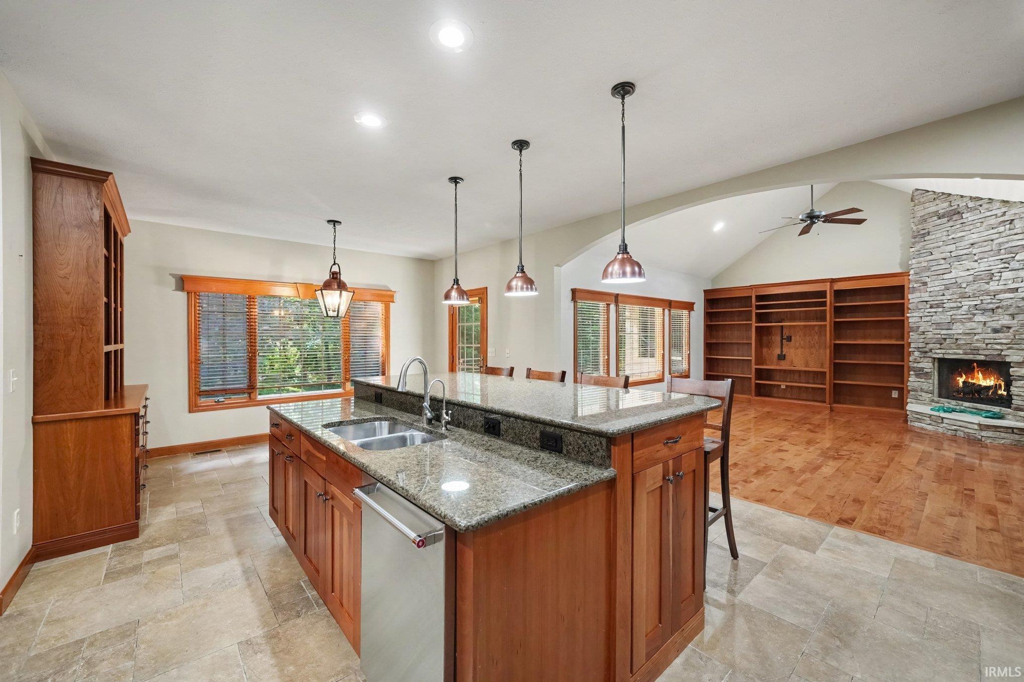 Gourmet kitchen showcasing a substantial center island with granite countertops, rich wood cabinetry, and pendant lighting