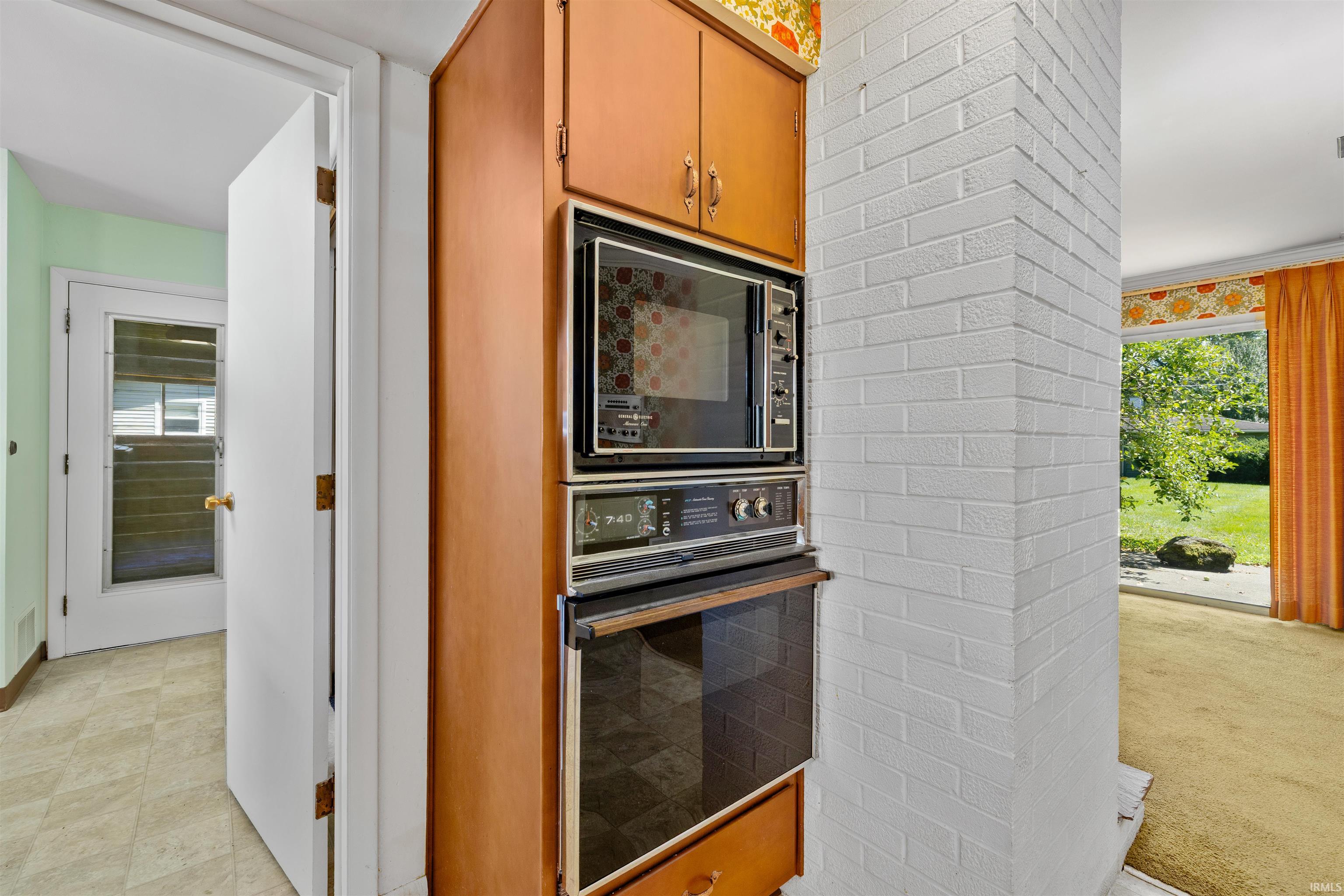 Built-in wall oven and microwave combination featuring wood-finish cabinetry and stainless steel appliance fronts