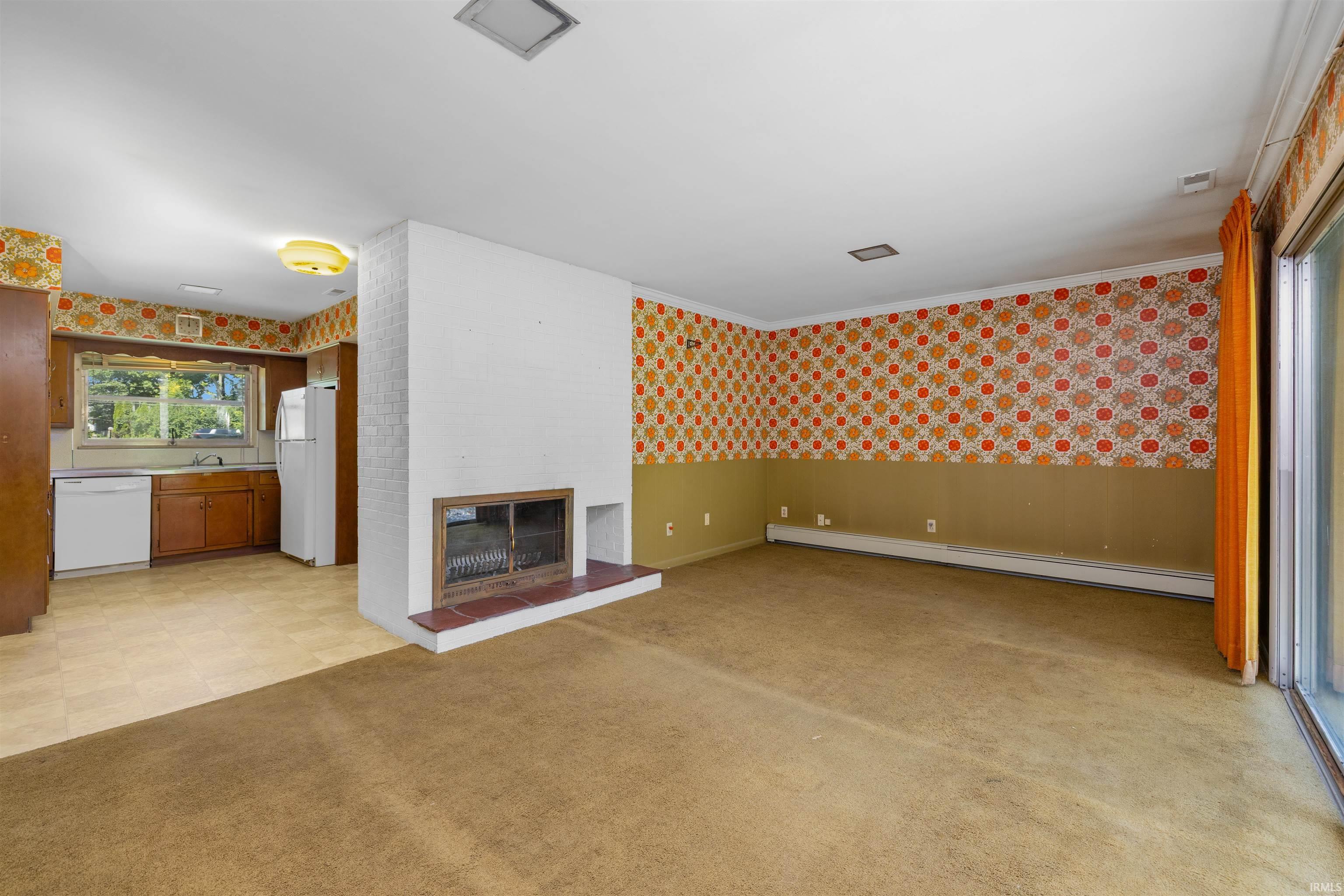 Spacious living area featuring wood-finish flooring, a decorative fireplace with tile surround, and abundant natural light from sliding glass doors