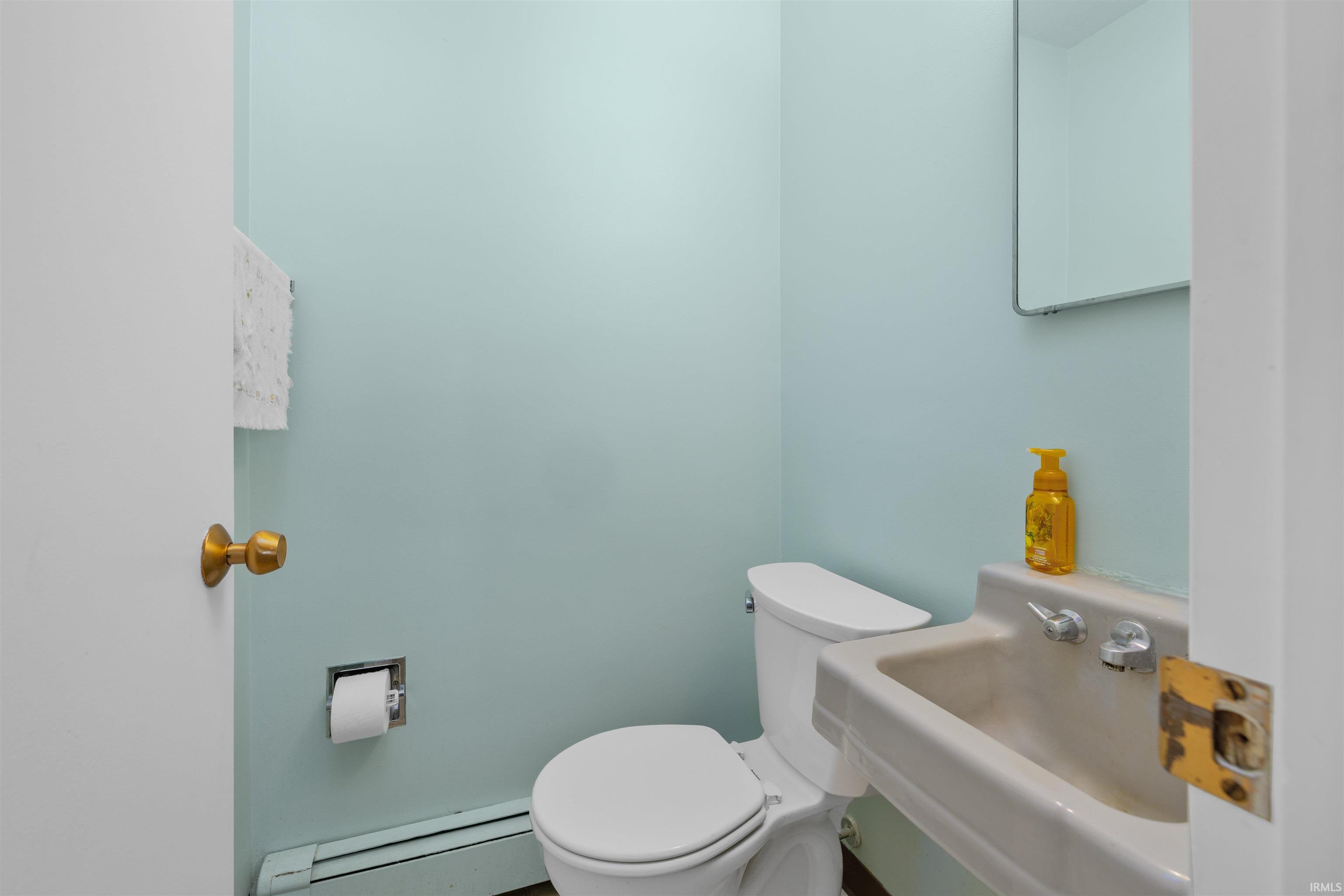 Compact half bath featuring a white porcelain toilet, neutral countertop with integrated sink, chrome fixtures, and soft blue-green wall finishes