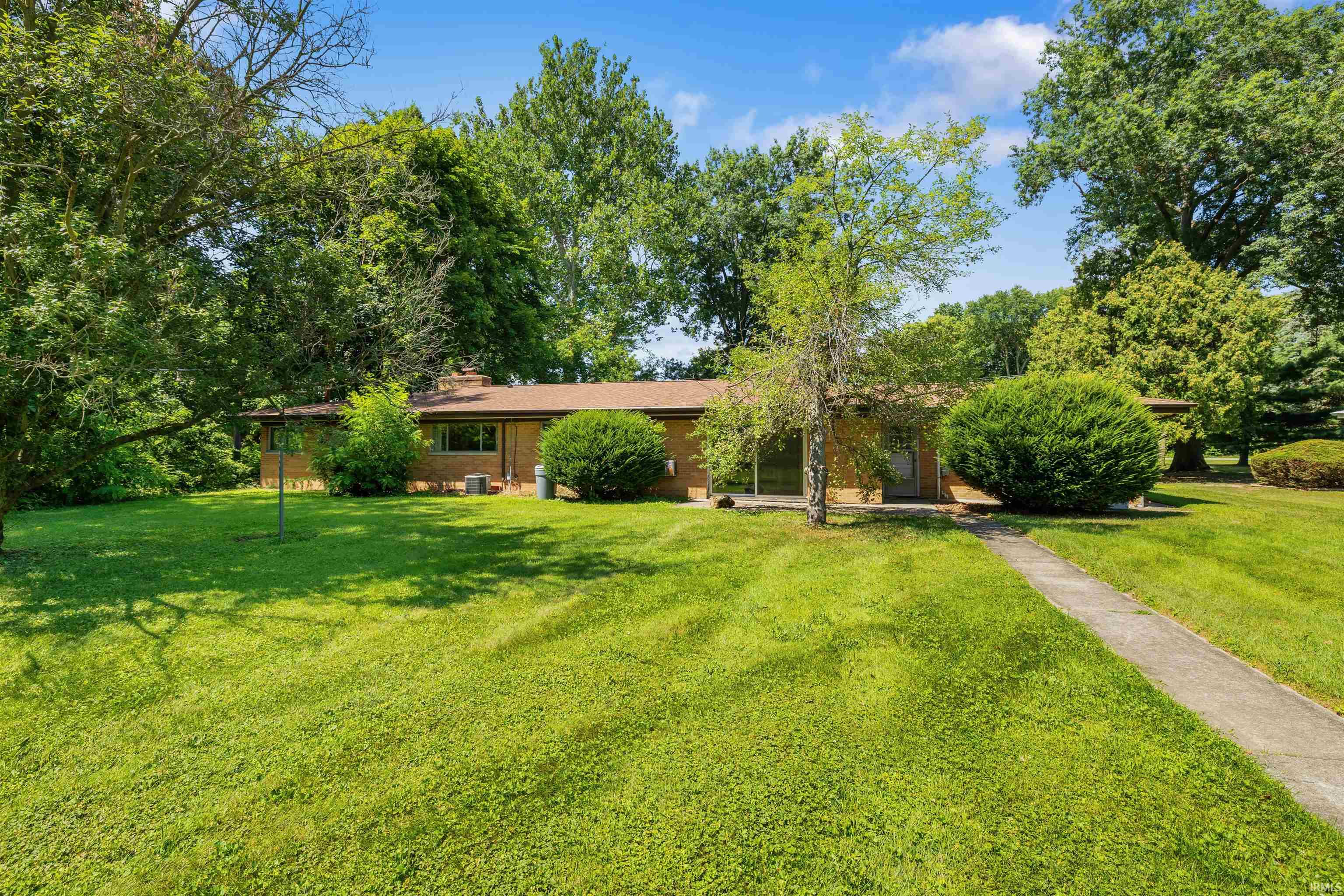 Ranch-style exterior with brick siding, a brown shingle roof, and a concrete pathway