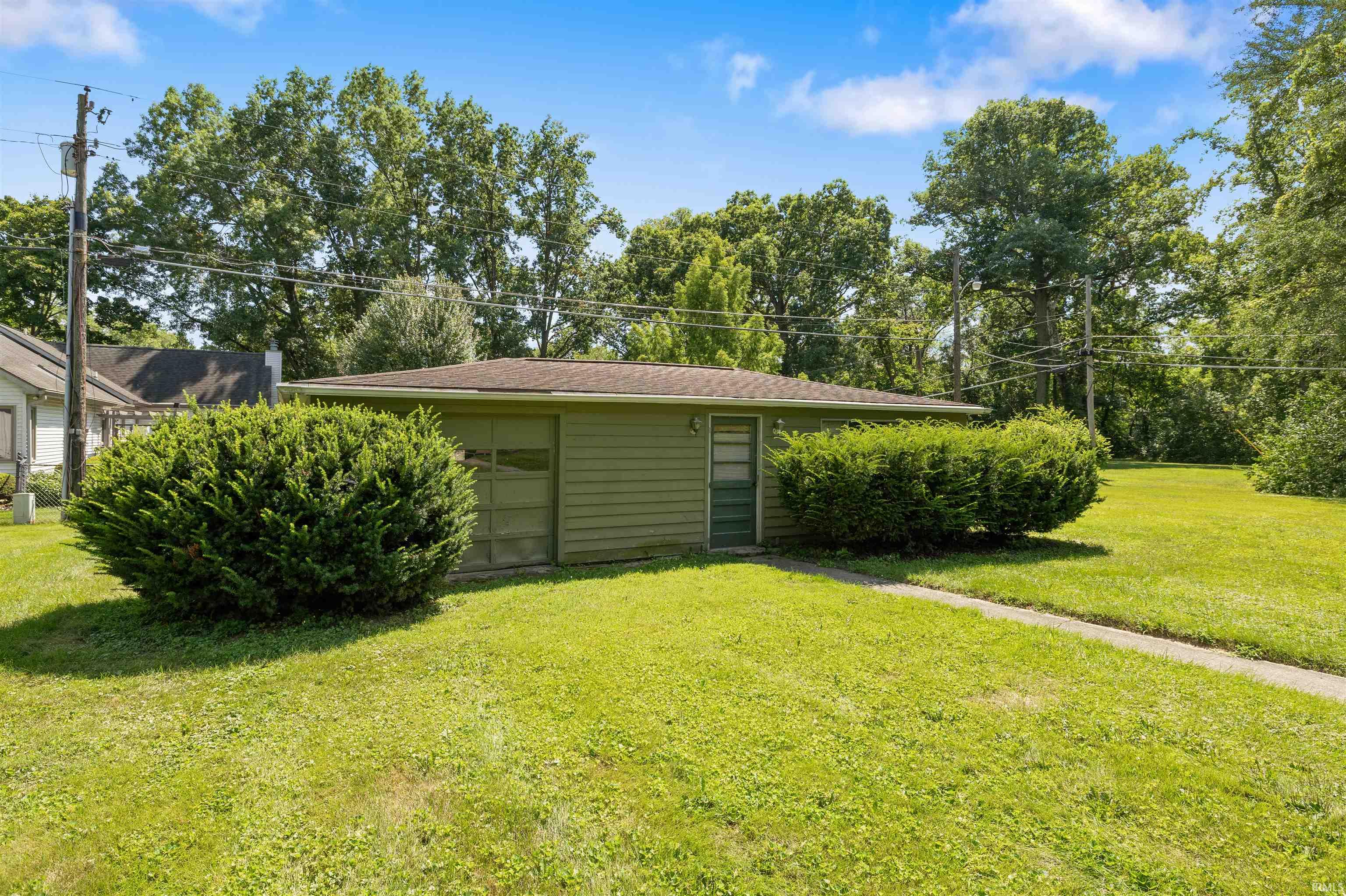 Detached garage with siding exterior, single garage door, and side entry door