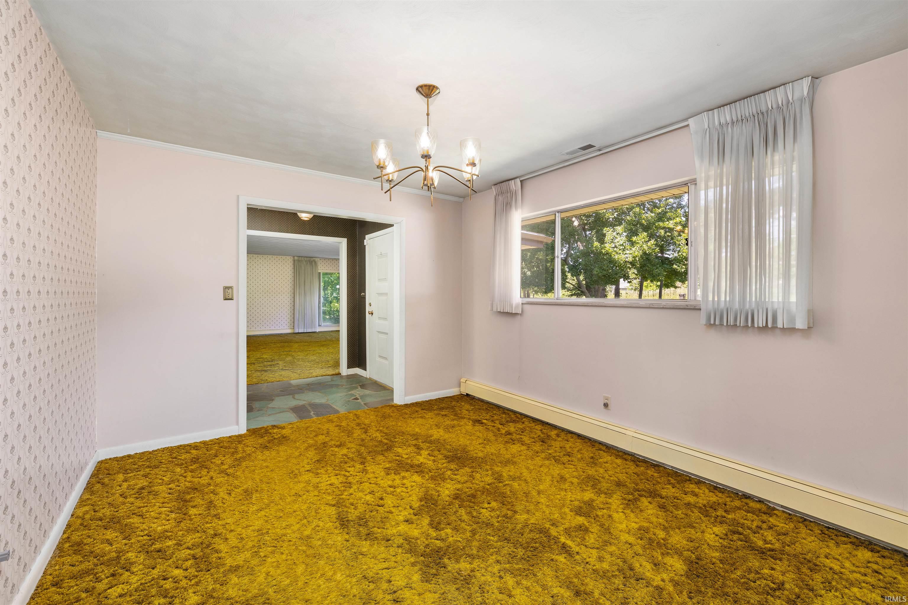 Interior room featuring a gold shag carpet, light pink painted walls, and one wall with patterned wallpaper