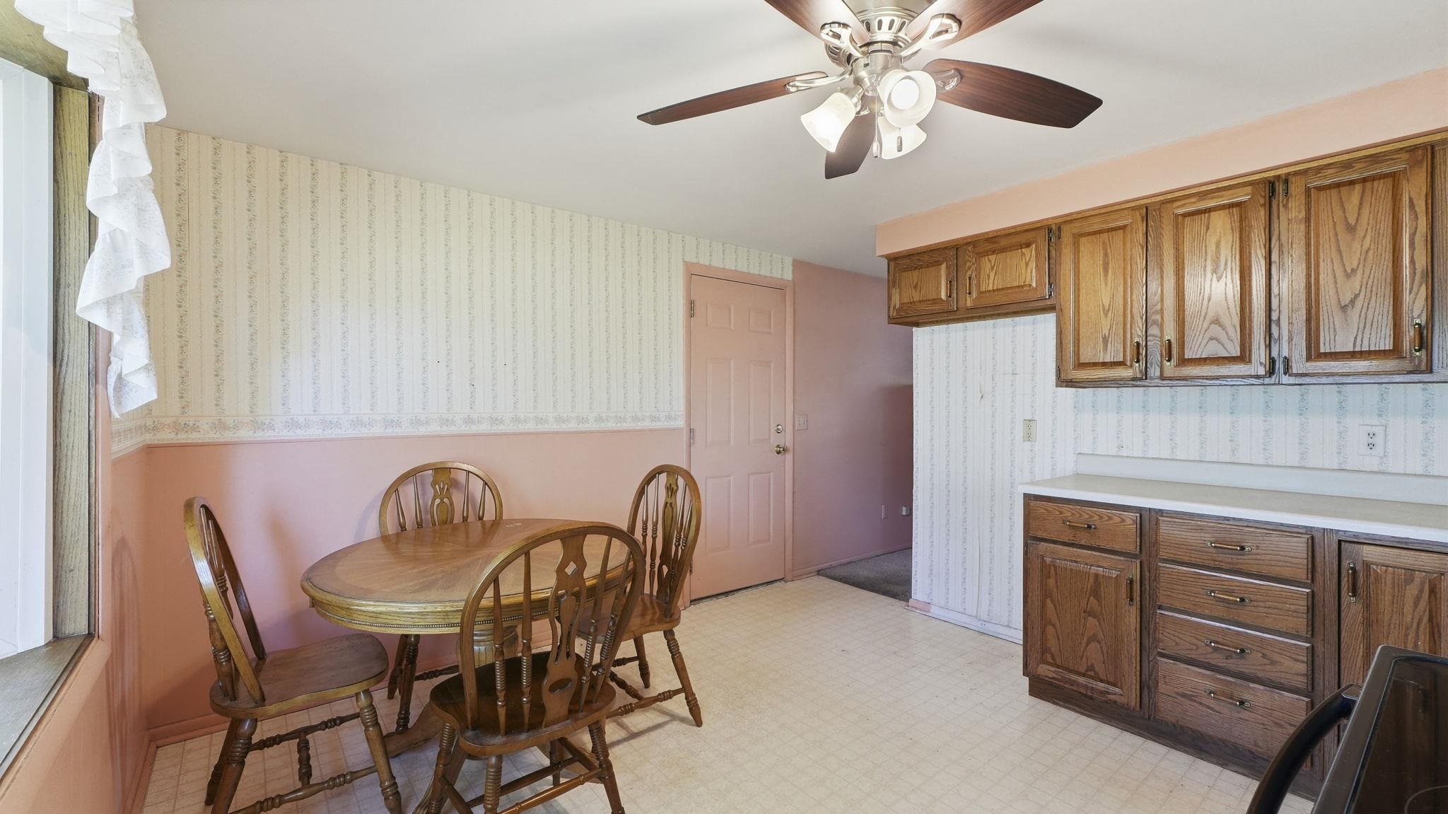 Spacious kitchen and dining area featuring wood cabinetry with ample storage, tile countertops, white appliances, and a round dining table with seating for four