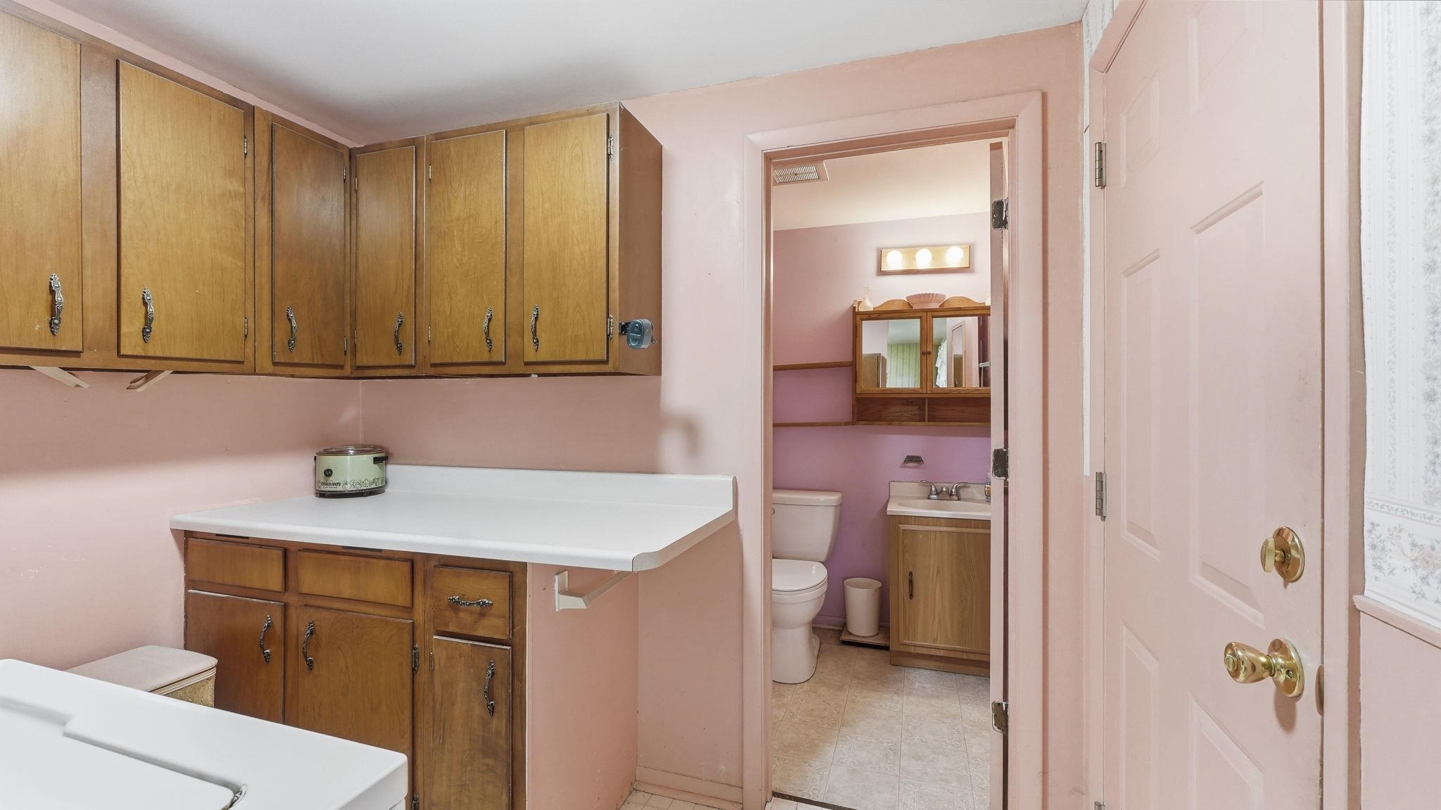 Dual-sink bathroom vanity featuring wood-finish cabinetry with ample storage, white countertop, and brass hardware