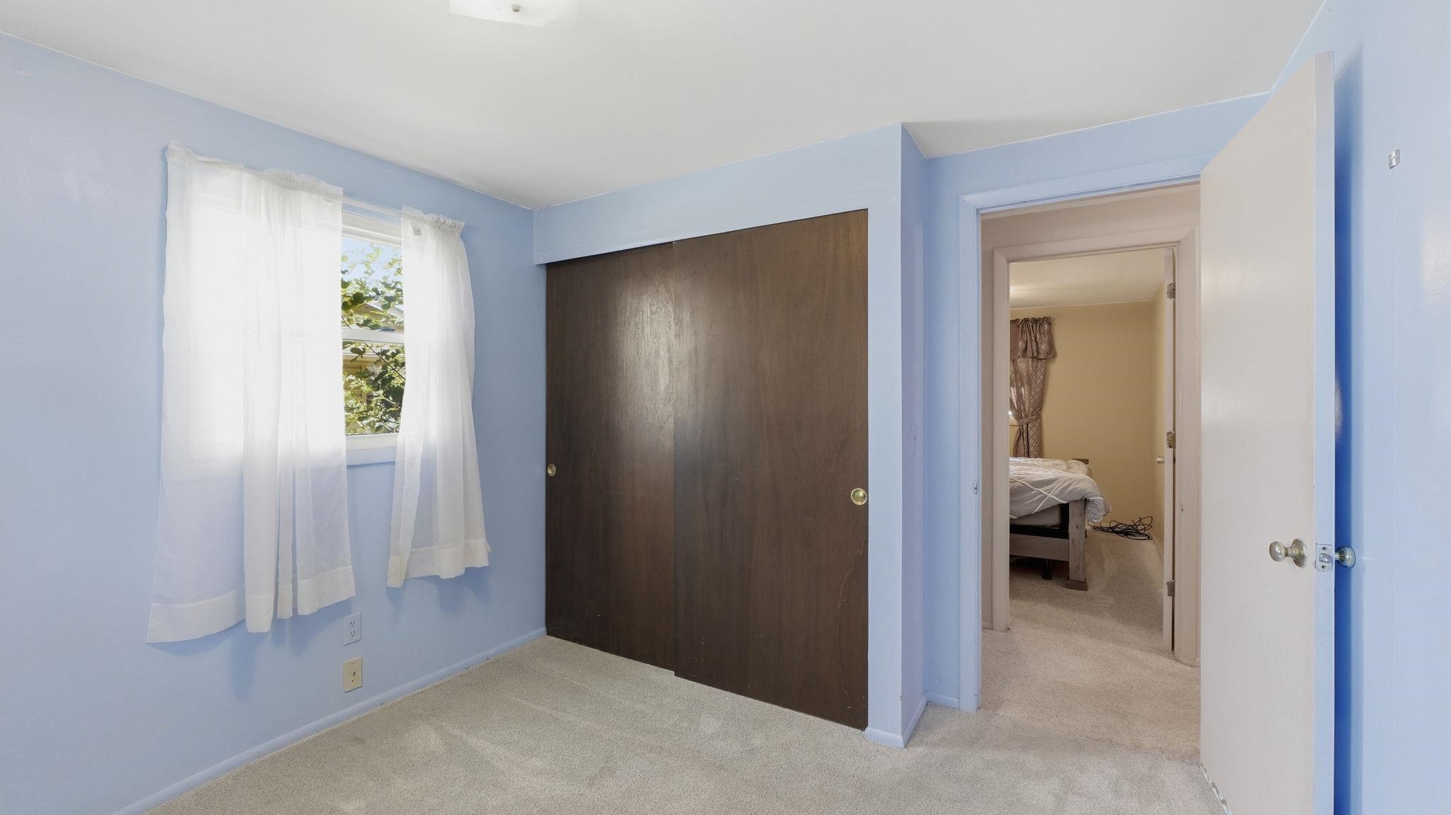 Spacious bedroom retreat featuring soft blue walls, neutral carpet flooring, and a large dark wood-finish closet door