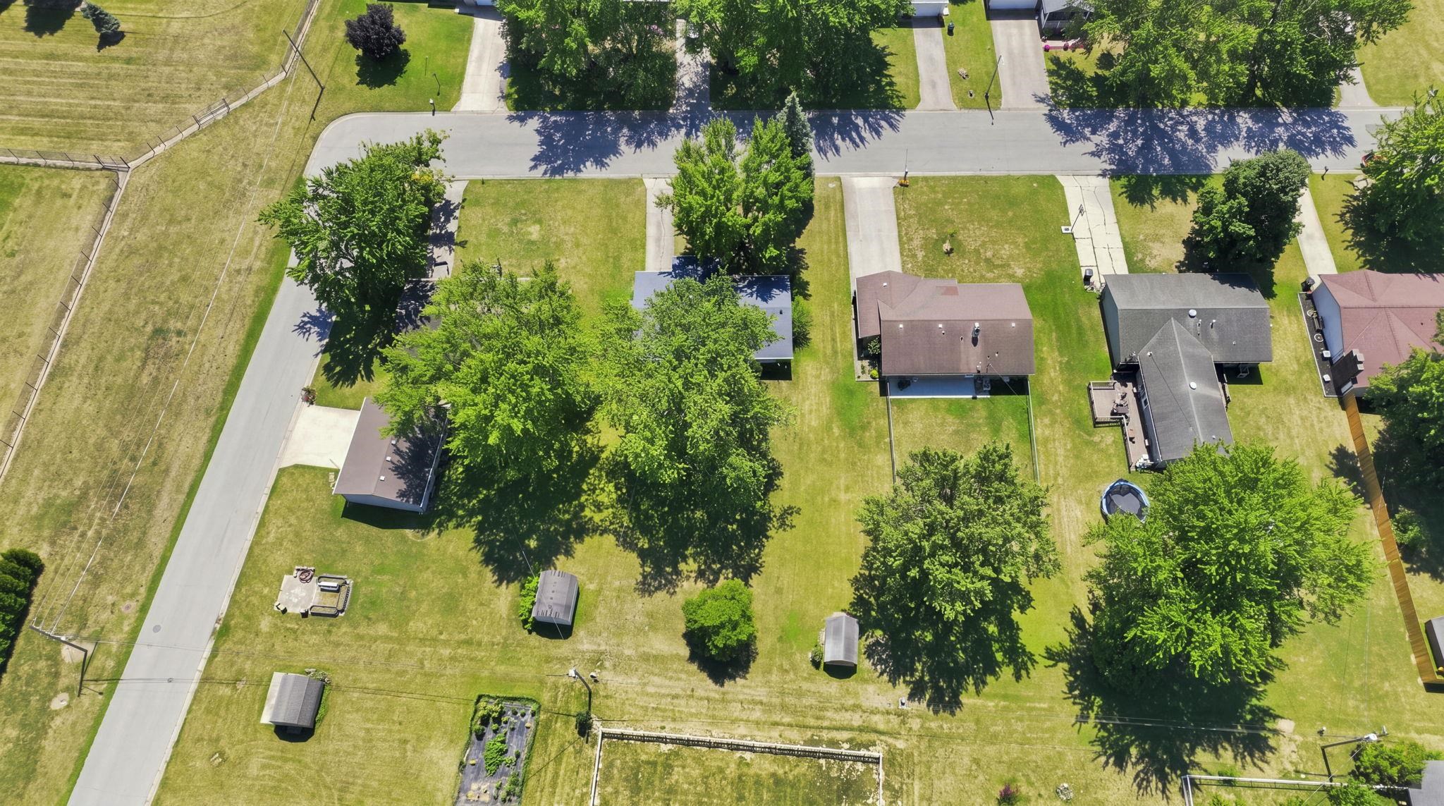 Expansive residential lot featuring mature shade trees, manicured lawn, and established landscaping