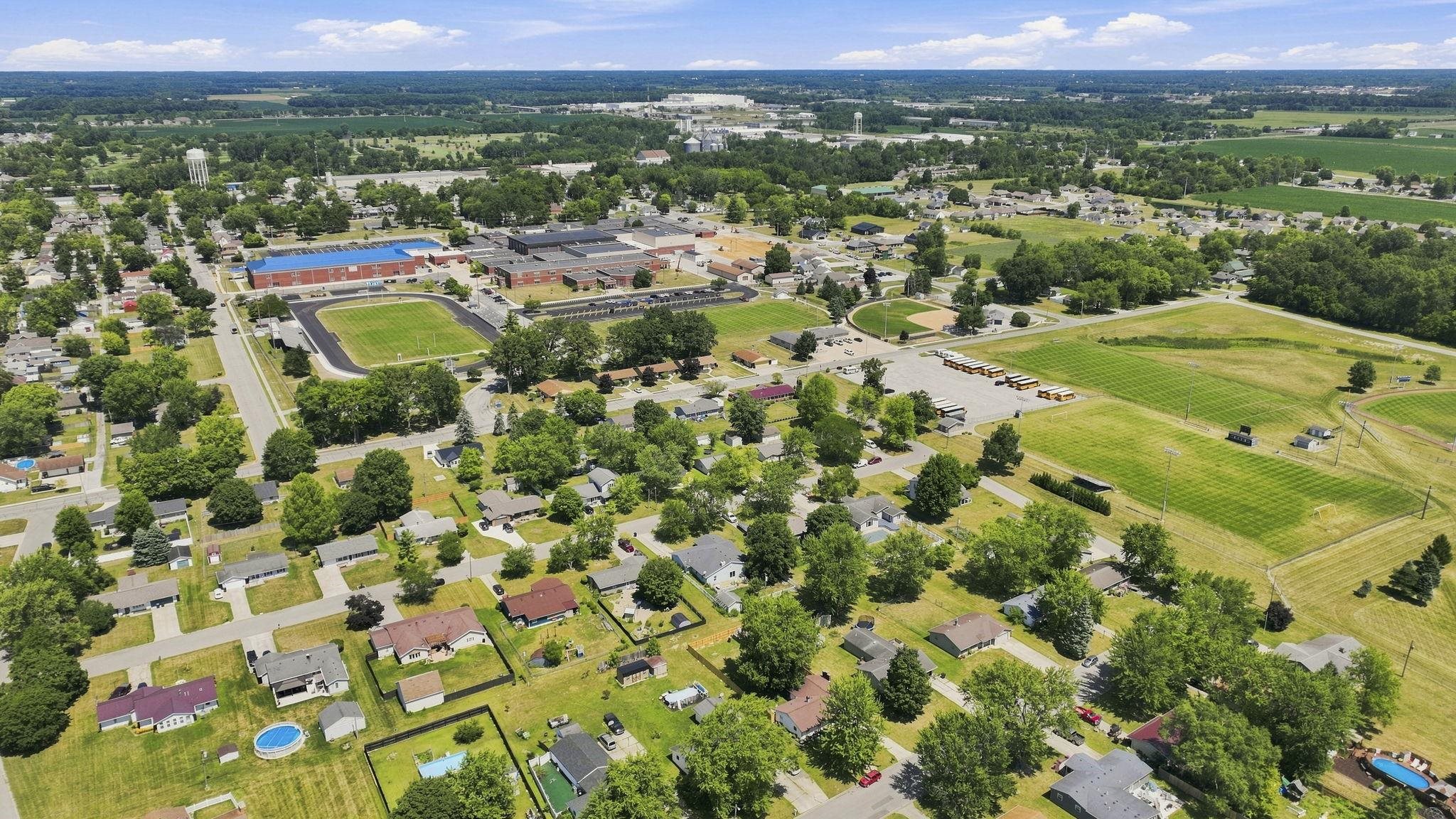 Aerial view of this residential property showcasing expansive grounds with mature landscaping, open lawn areas, and established trees throughout