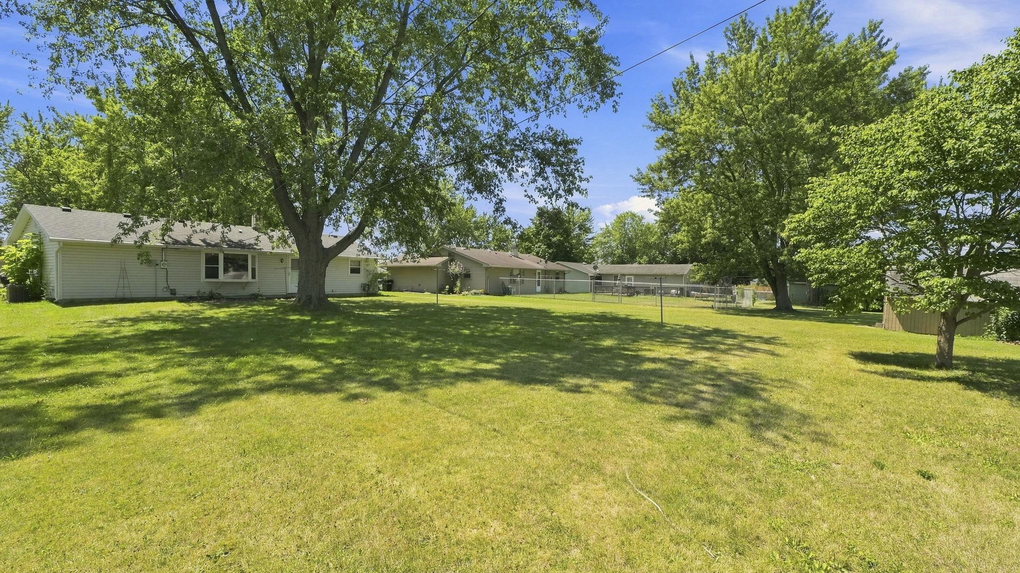 Expansive grounds featuring mature shade trees, manicured lawn, and single-story ranch-style residence with covered entry