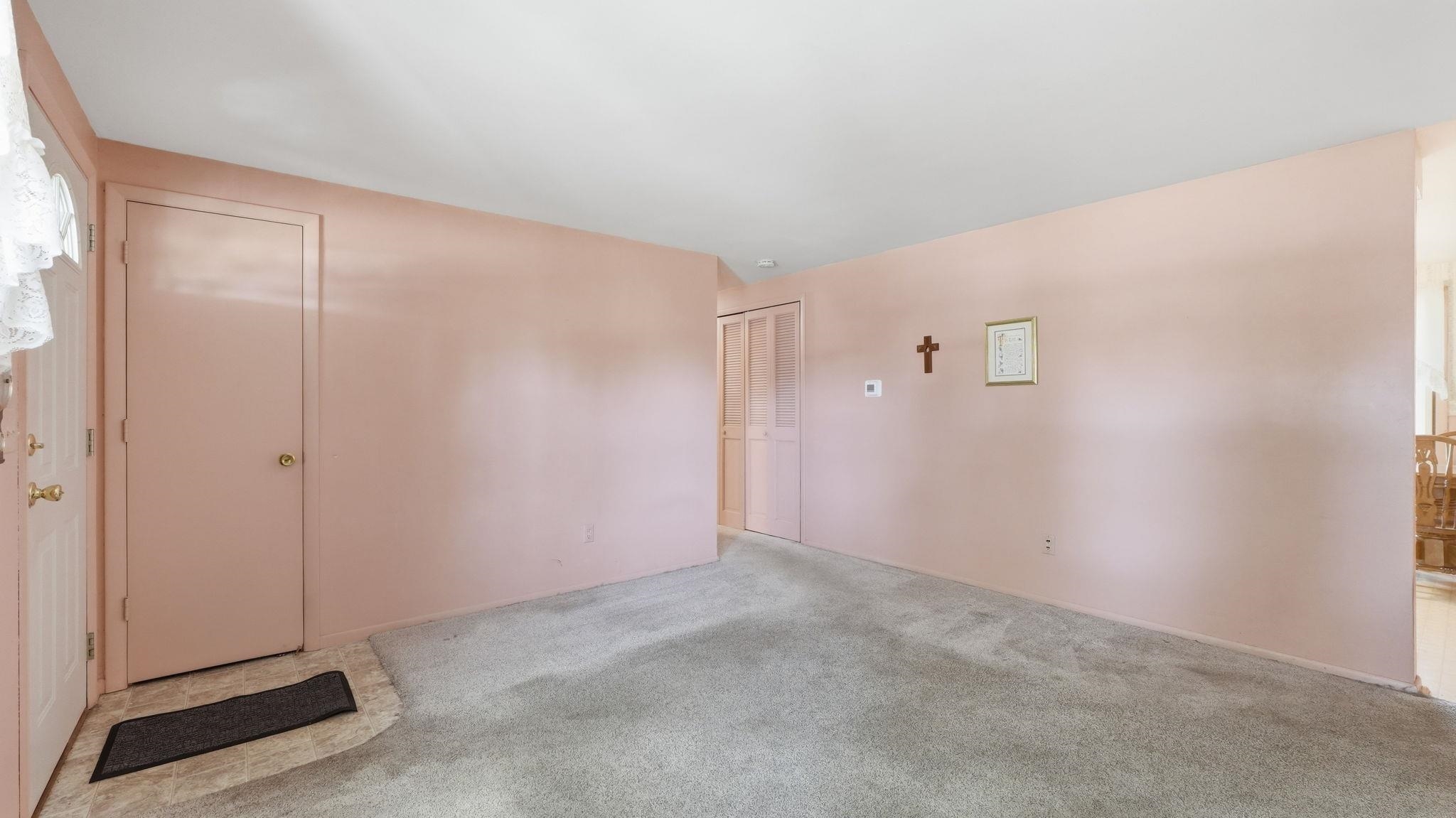 Spacious bedroom featuring soft pink walls, neutral carpet flooring, and ample natural light from multiple windows