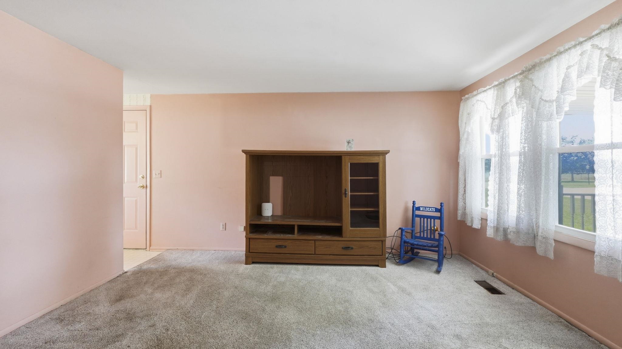 Spacious living room showcasing neutral-toned walls, plush carpeting, and abundant natural light from large windows