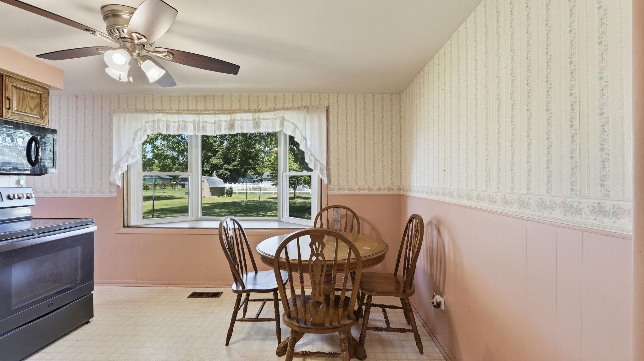 Charming kitchen and dining area bathed in natural light through expansive multi-pane windows overlooking the grounds