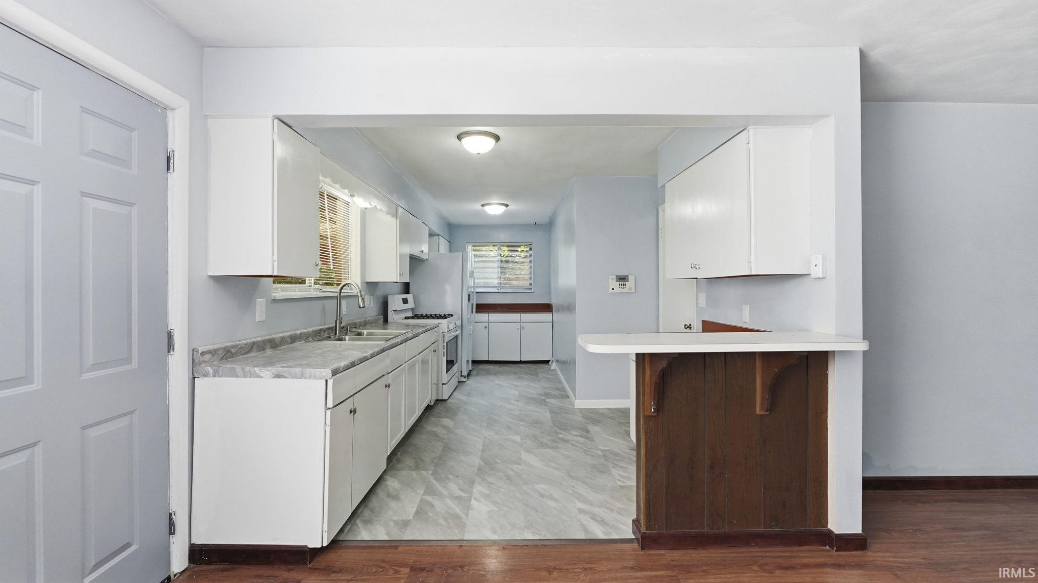 Kitchen featuring white cabinetry, light countertops, and a stainless steel sink with a gooseneck faucet