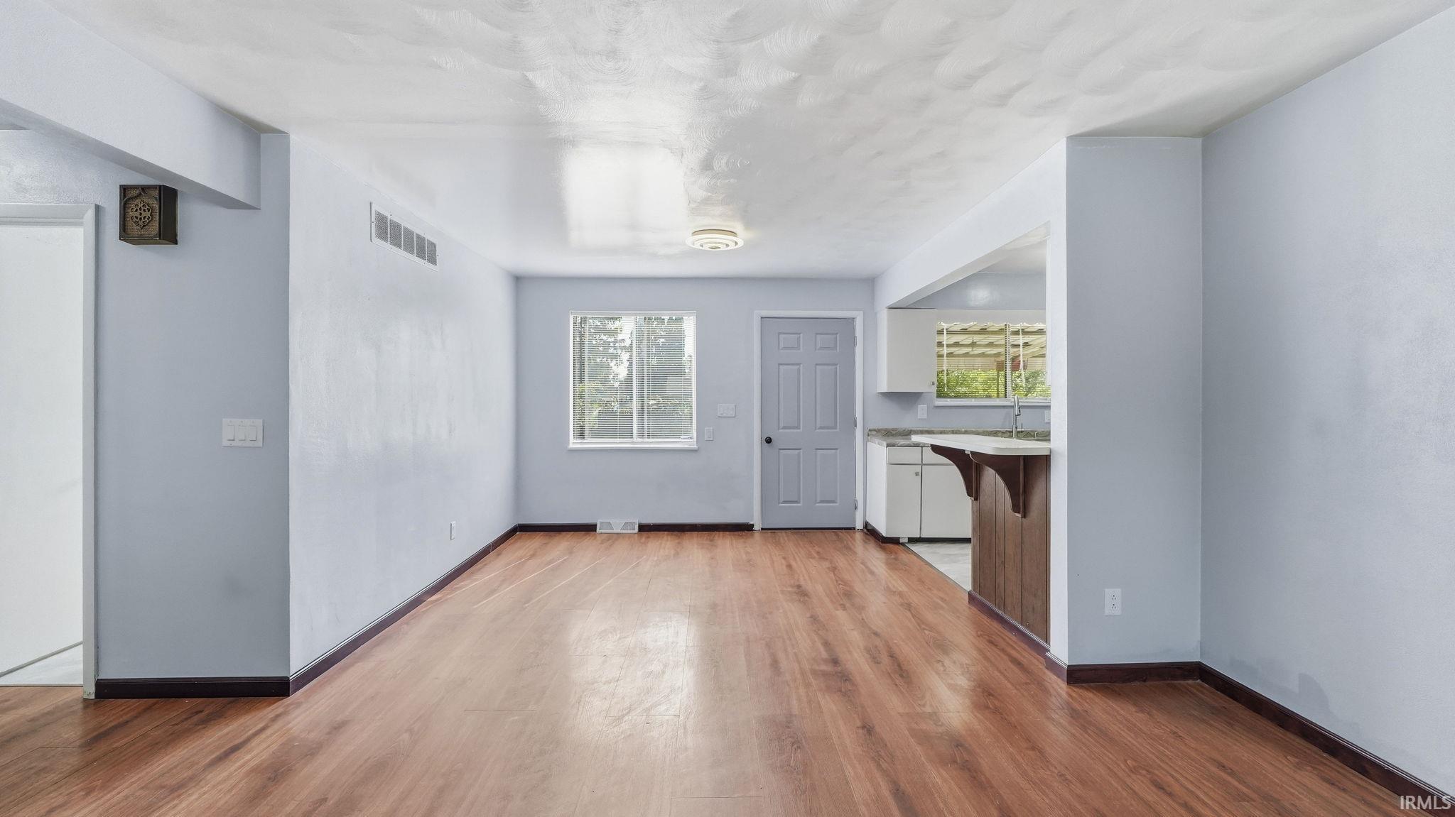 Open-concept living area with wood-finish flooring, light-colored walls, and a textured ceiling