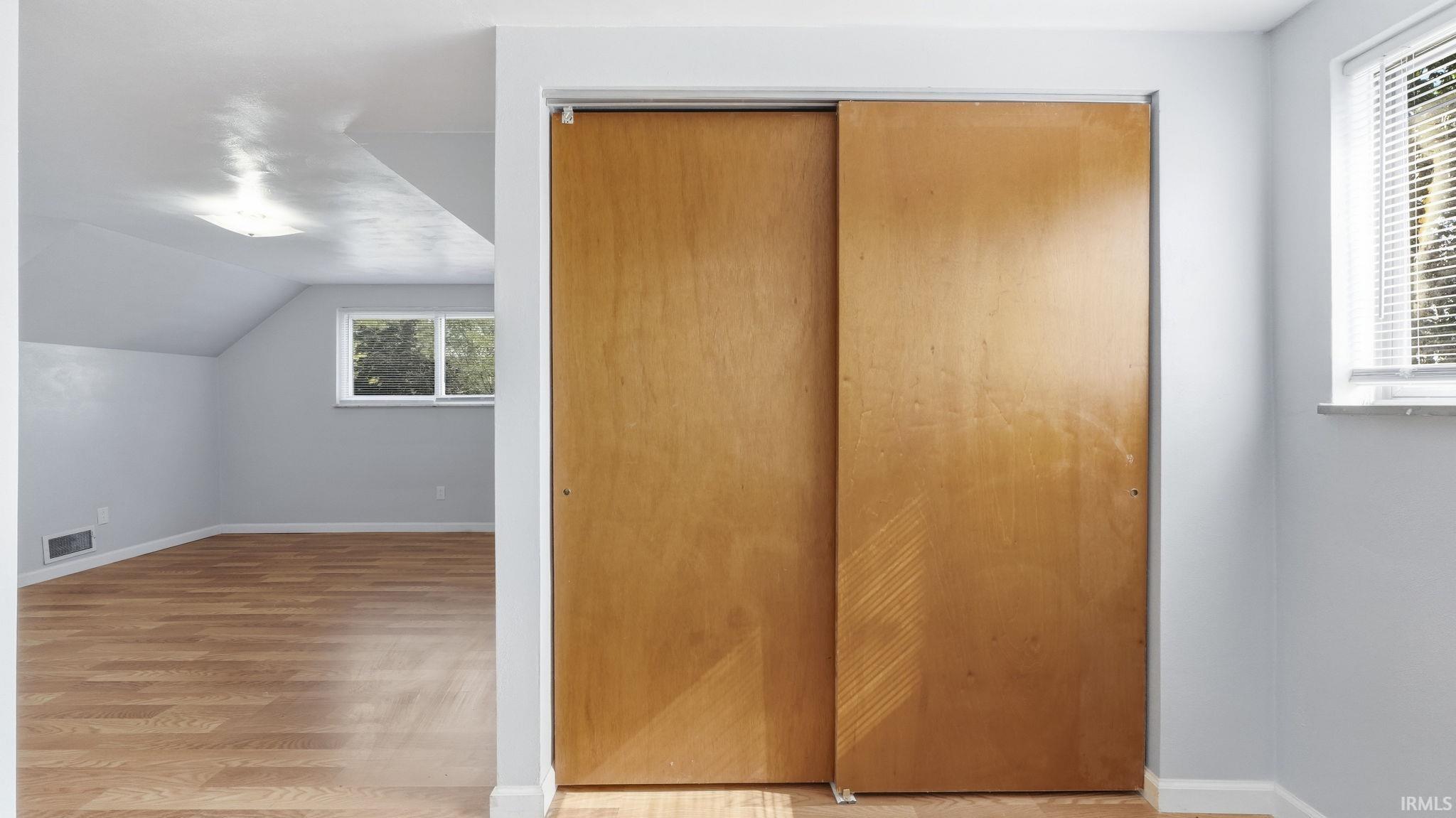 Bedroom featuring wood-finish flooring, light grey painted walls, and a sloped ceiling