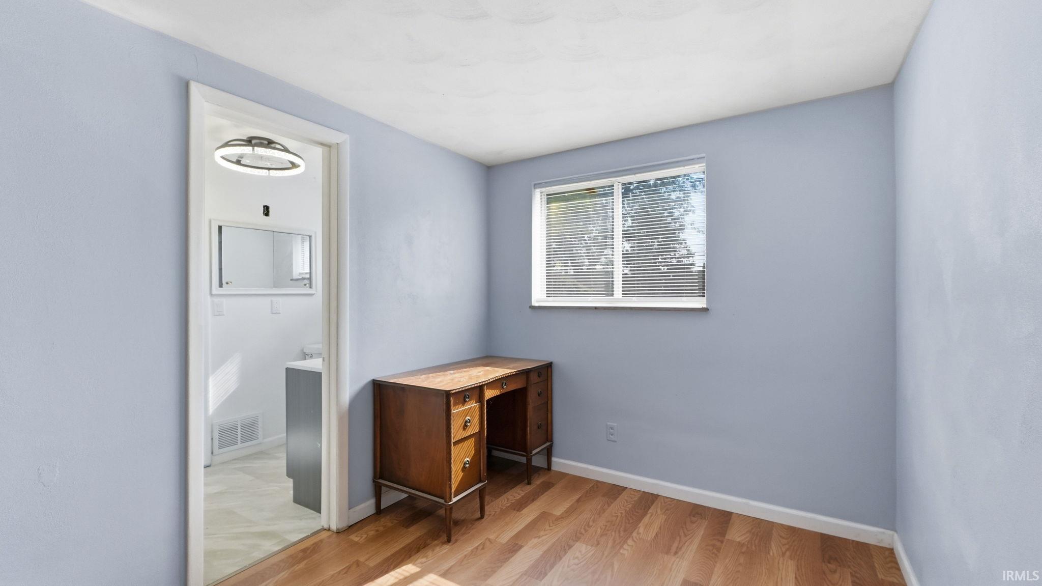 Room featuring light blue walls, wood-finish flooring, and a white ceiling
