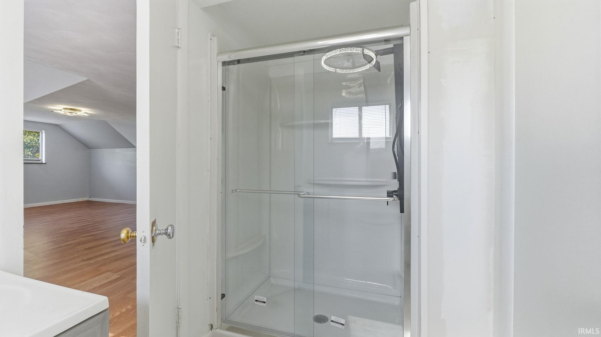 Glass-enclosed shower with a rainfall showerhead and integrated shelving