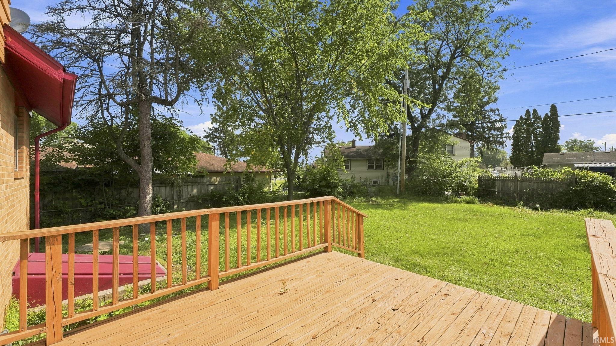 Spacious outdoor deck with natural wood railing overlooking a grassy yard