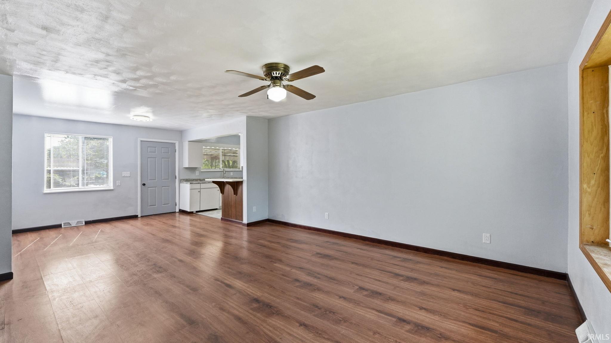 Open-concept living space featuring wood-finish flooring and light-toned walls