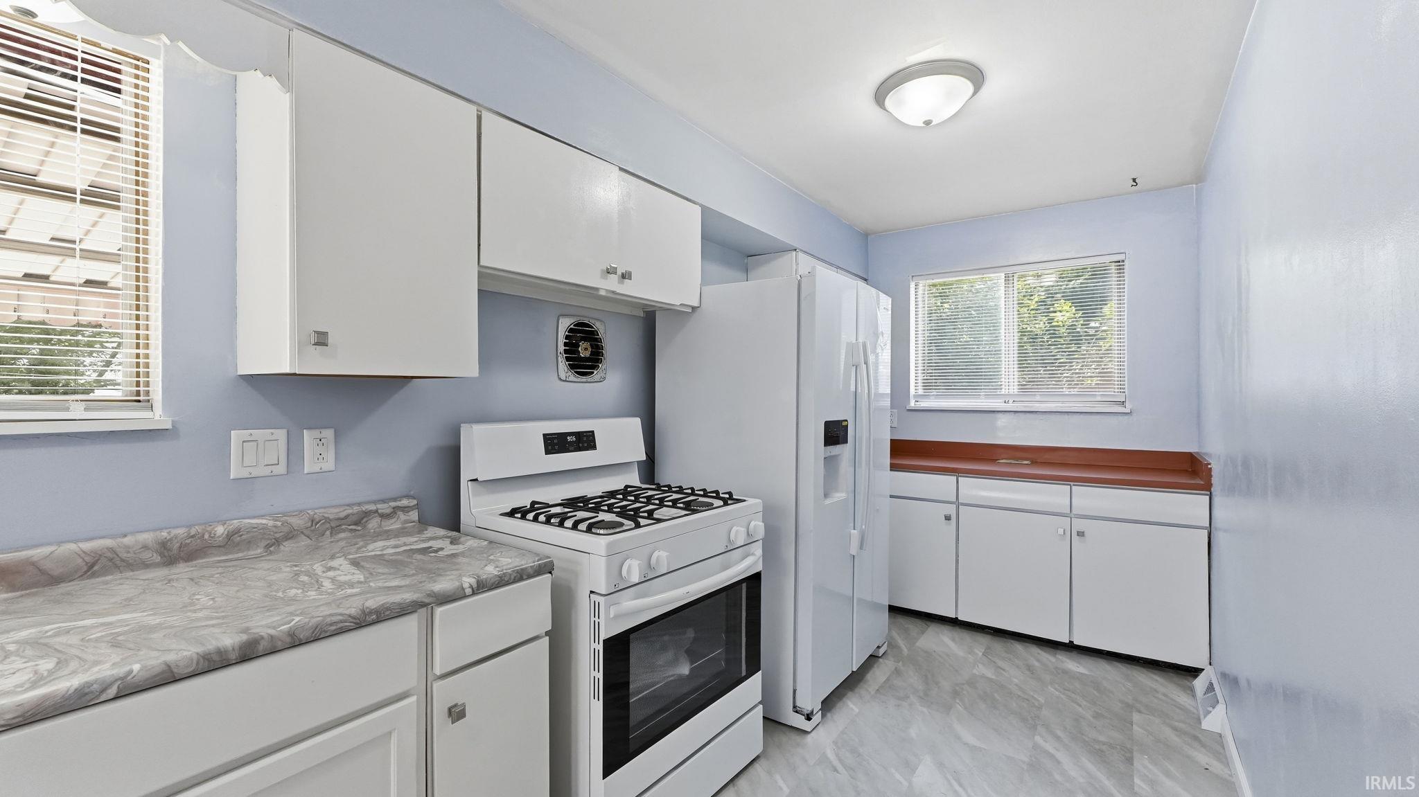 Kitchen featuring white cabinetry and appliances, a gas range, a refrigerator with ice and water dispenser, and a window