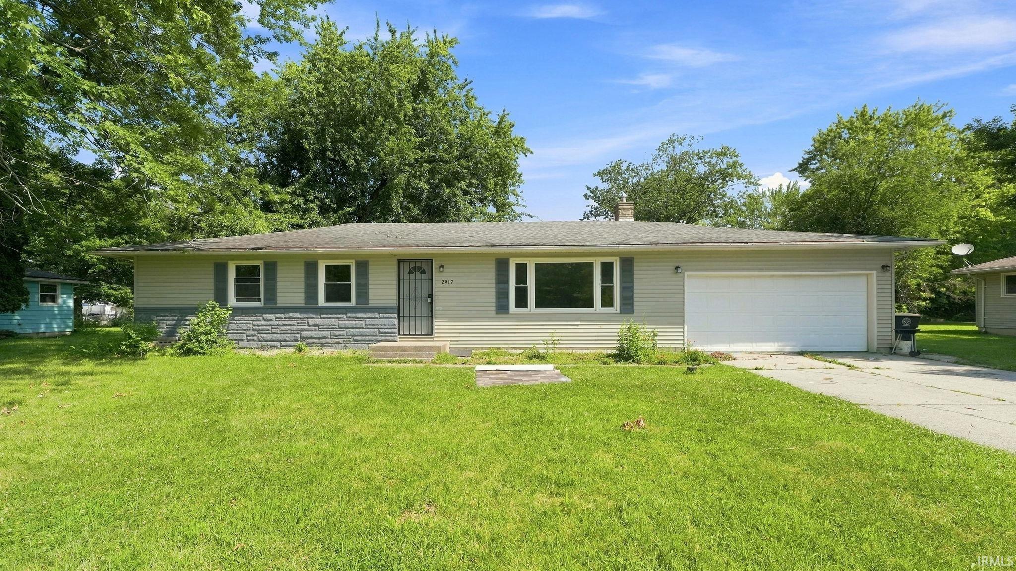 Ranch-style residence featuring light-colored siding and a stone facade accent