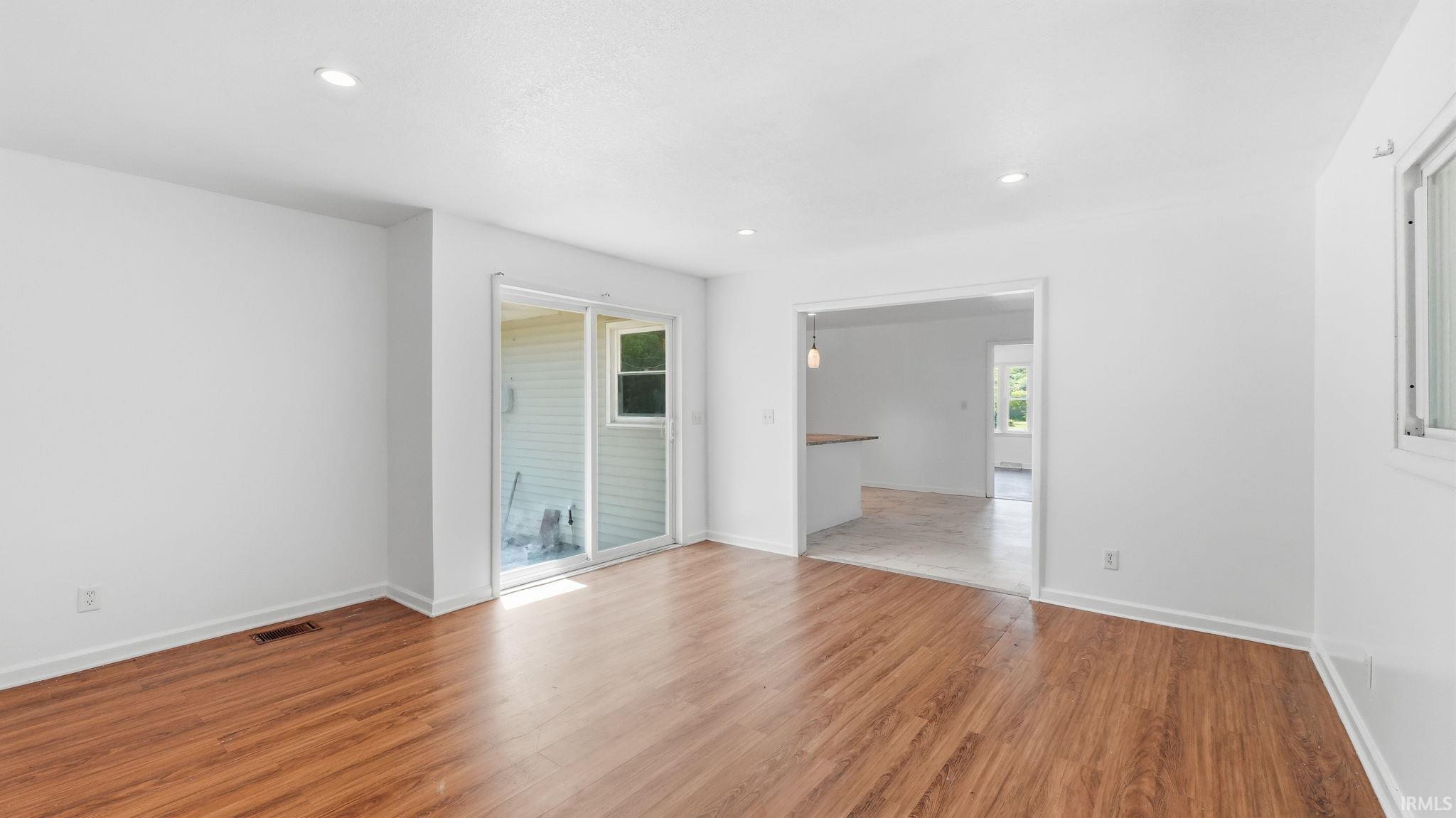 Open-concept living area featuring wood-finish flooring, recessed lighting, and white walls