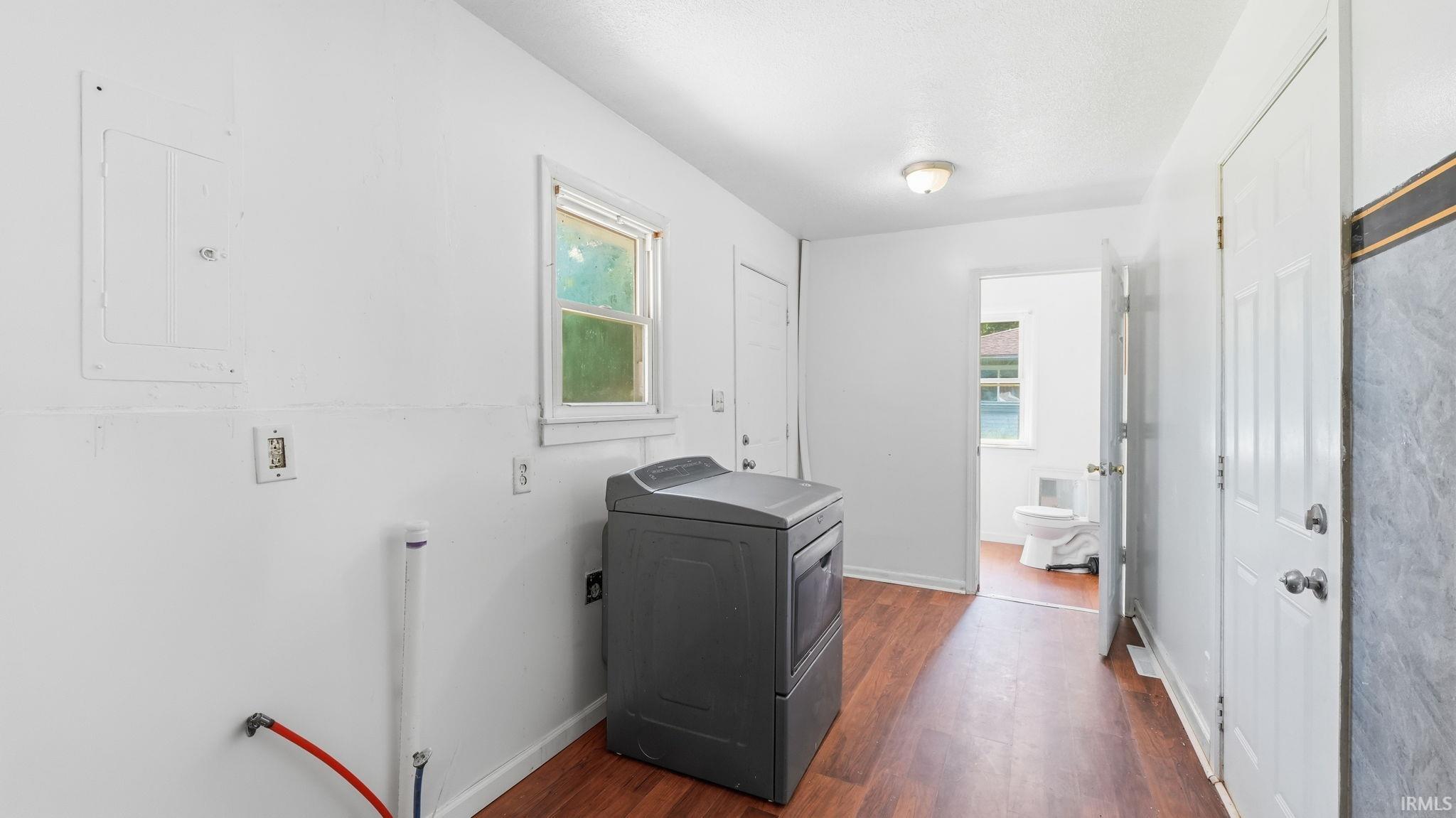Utility room featuring wood-finish flooring, white walls, and a window with exterior views