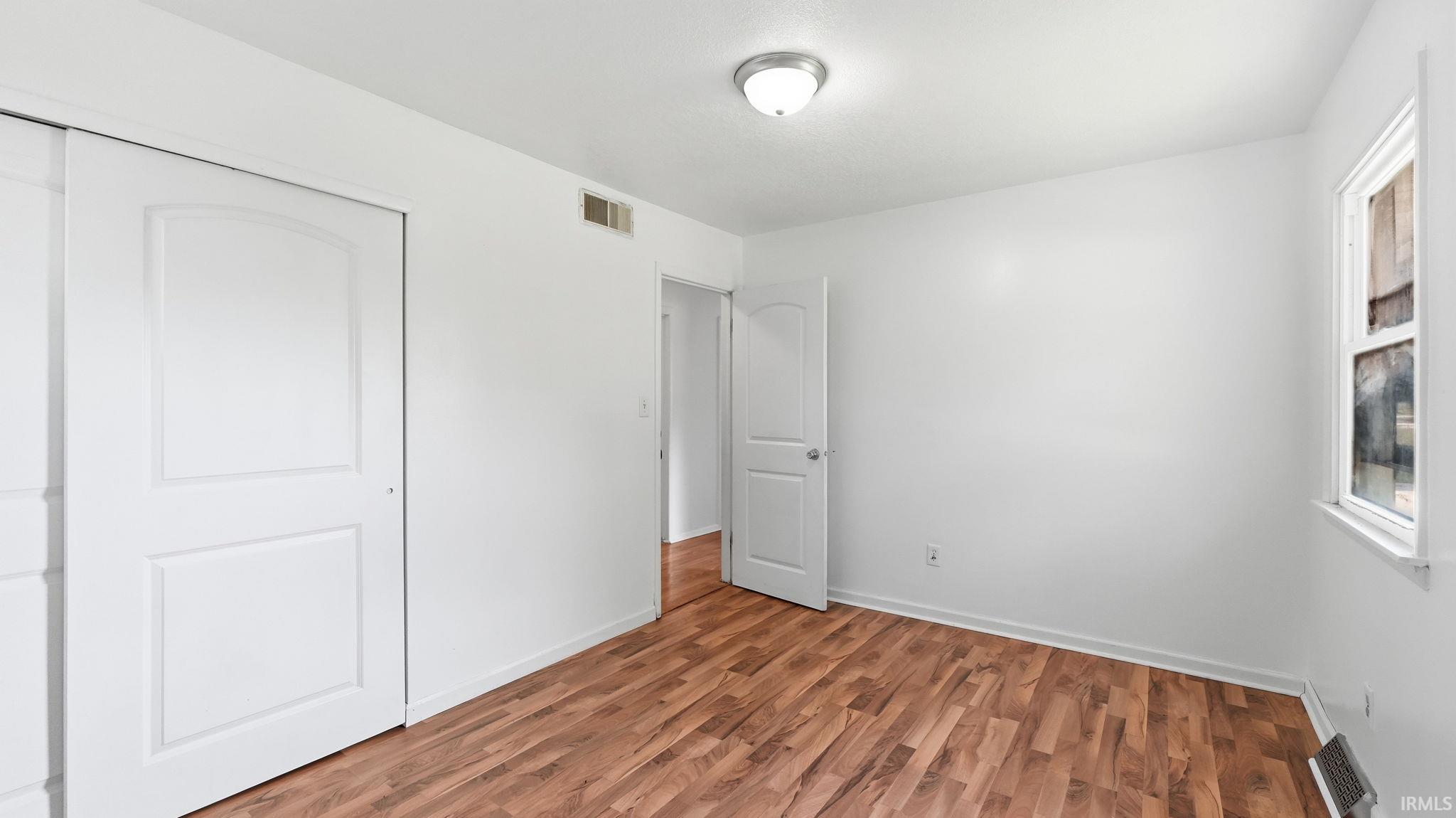Room featuring wood-finish flooring, white walls, and a ceiling-mounted light fixture