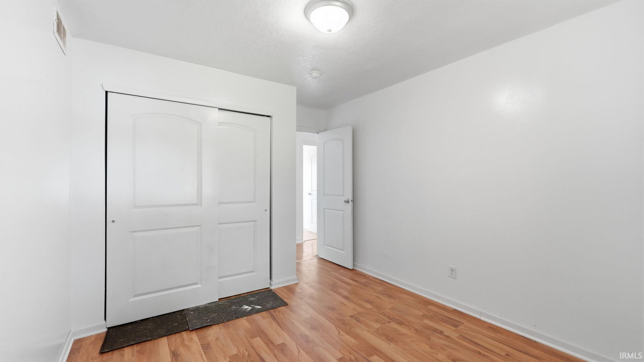 Interior room featuring wood-finish flooring, white walls, and a ceiling-mounted light fixture