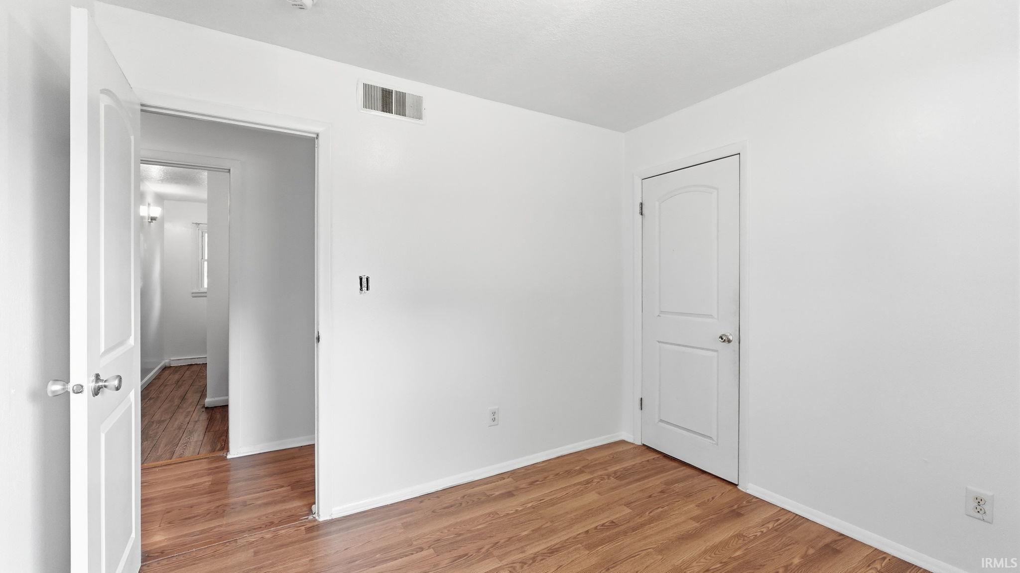 Room featuring wood-finish flooring, white walls, and bright white trim