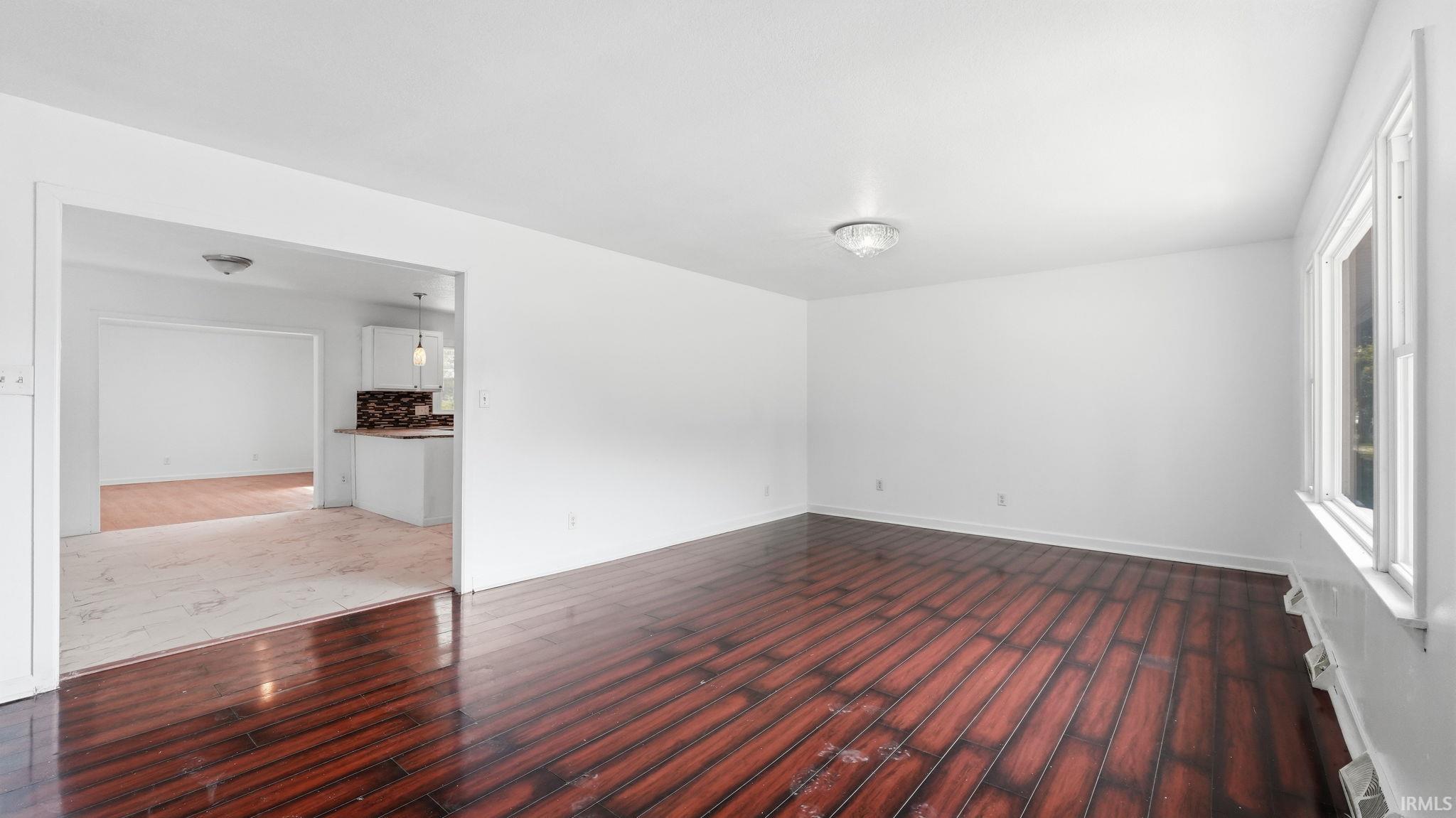 Spacious interior featuring wood-finish flooring, white walls, and a large window providing natural light