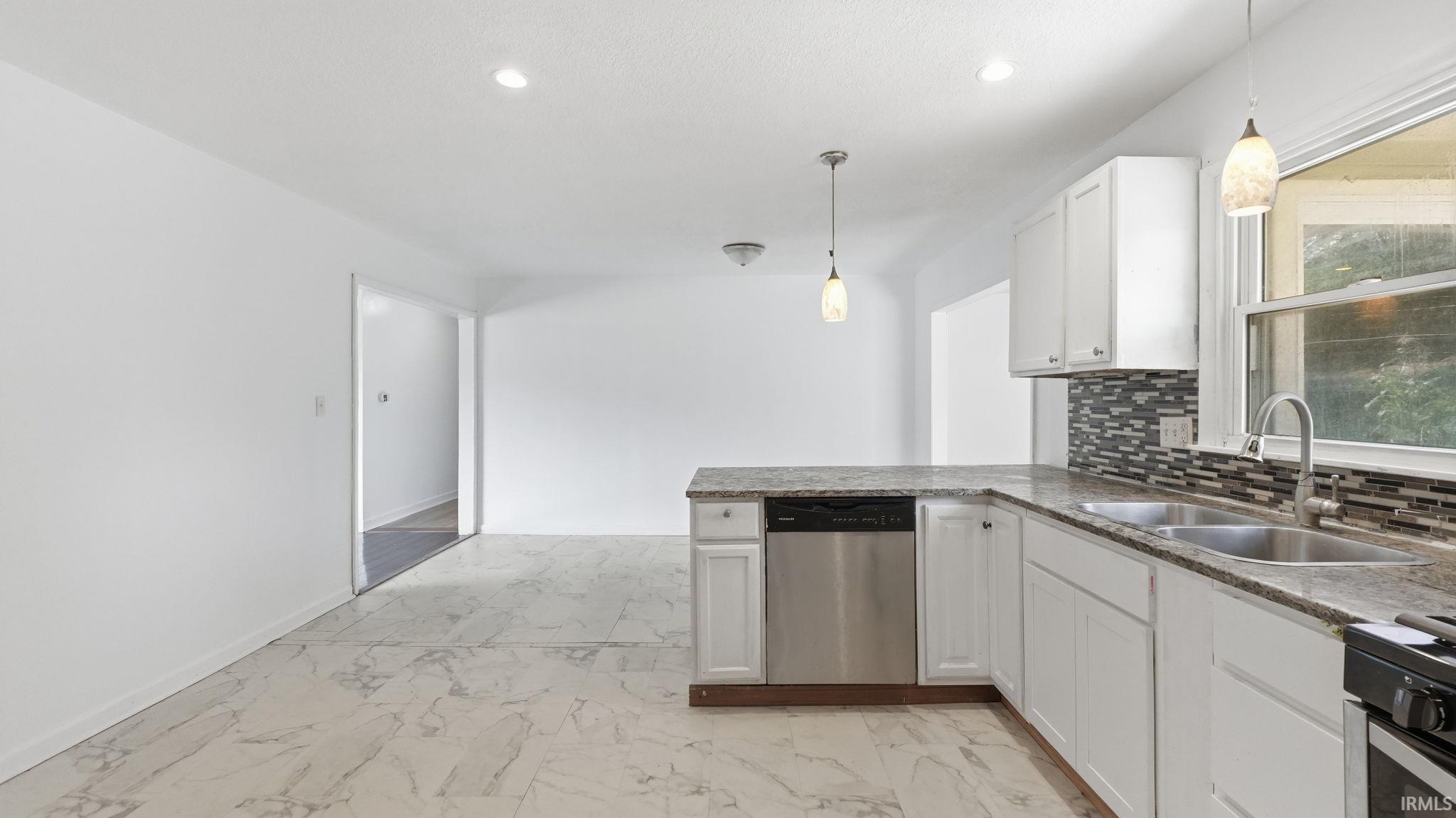 Contemporary kitchen featuring white cabinetry, a stainless steel dishwasher, a dual basin sink, a mosaic tile backsplash, and overhead pendant lighting