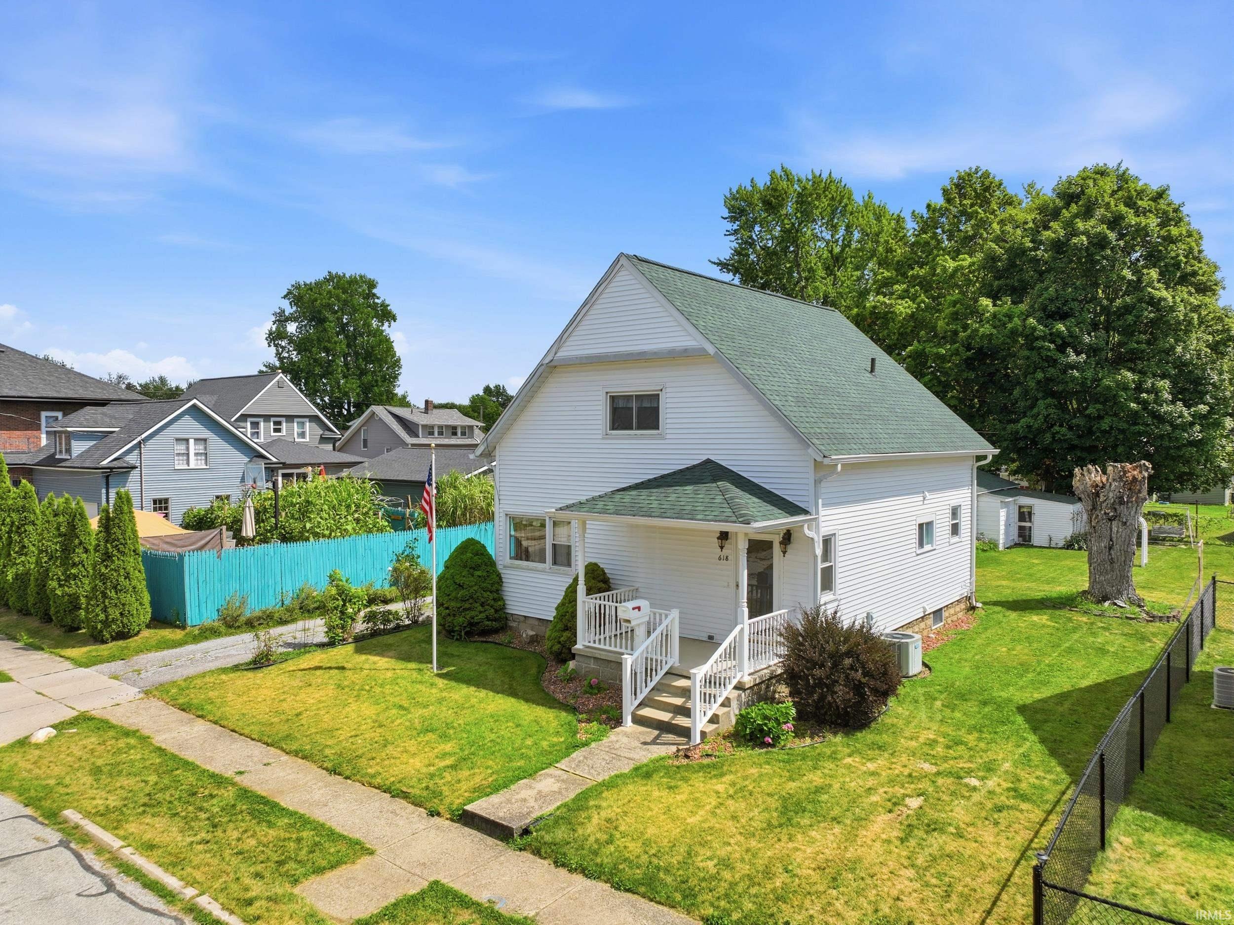 White siding exterior with a dark green gabled roof, featuring a covered porch entryway