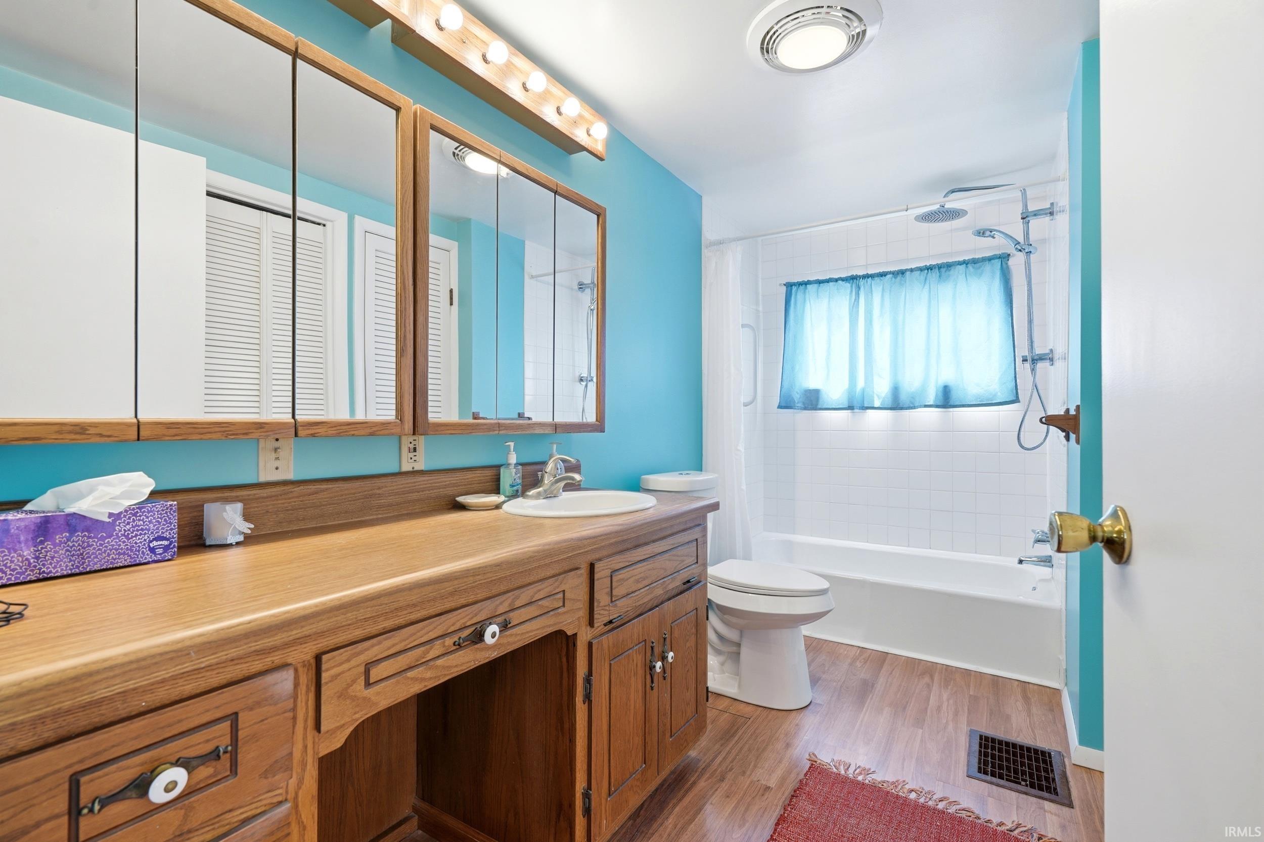 Spacious vanity with wood-finish countertop, integrated sink, and ample storage cabinetry
