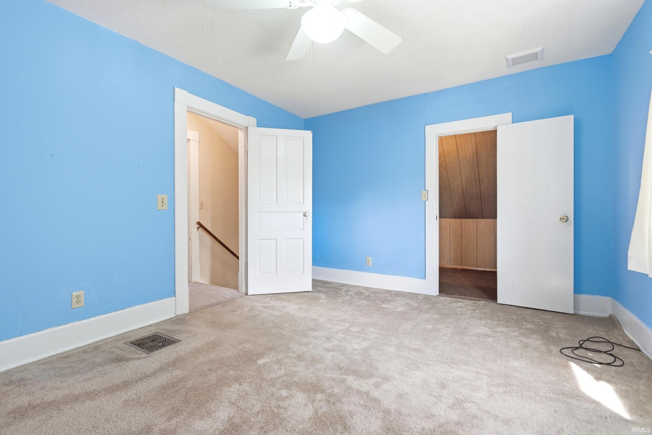 Carpeted room with blue walls, white trim, and a ceiling fan