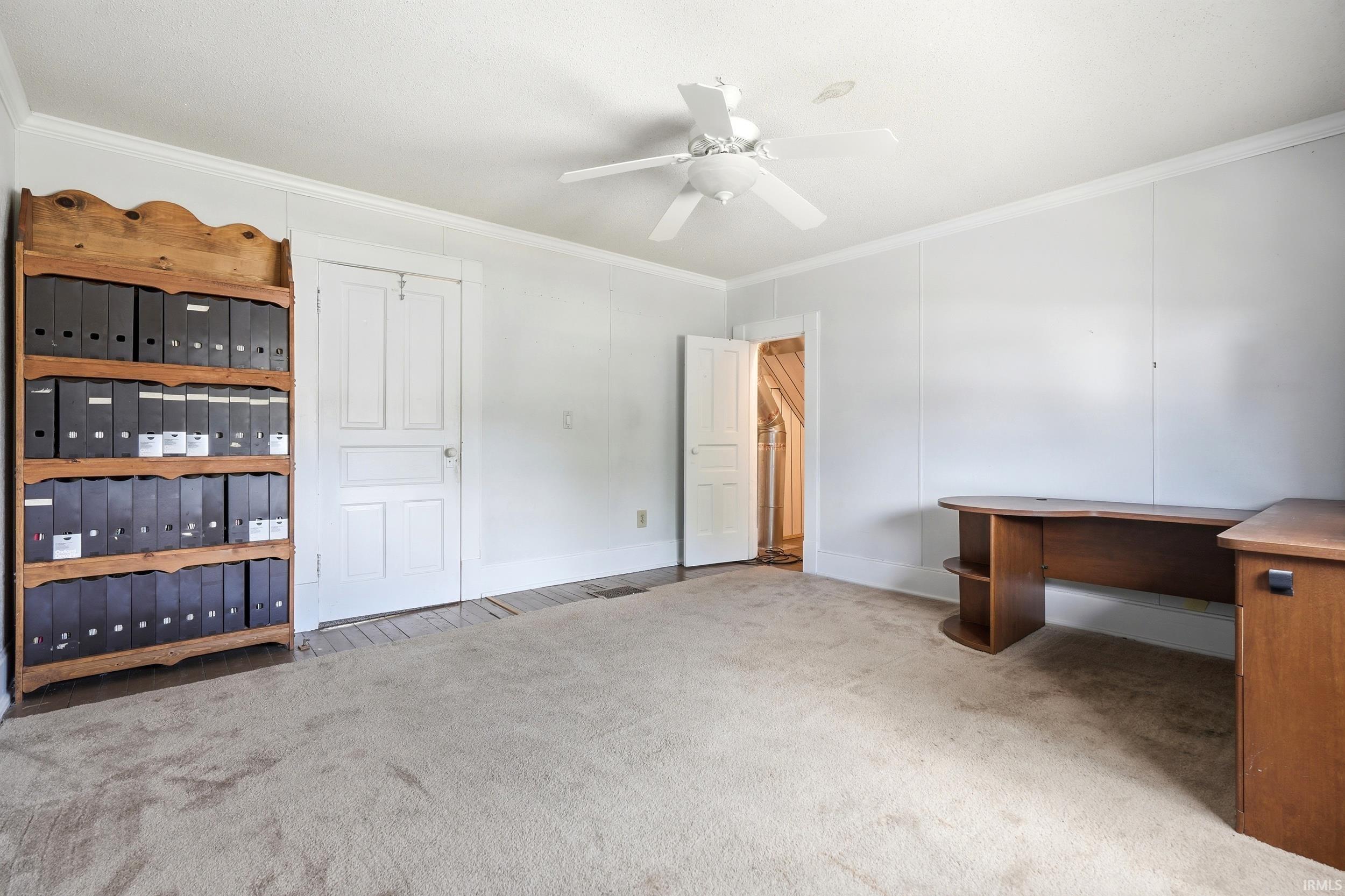 Carpeted room with white paneled walls and crown molding