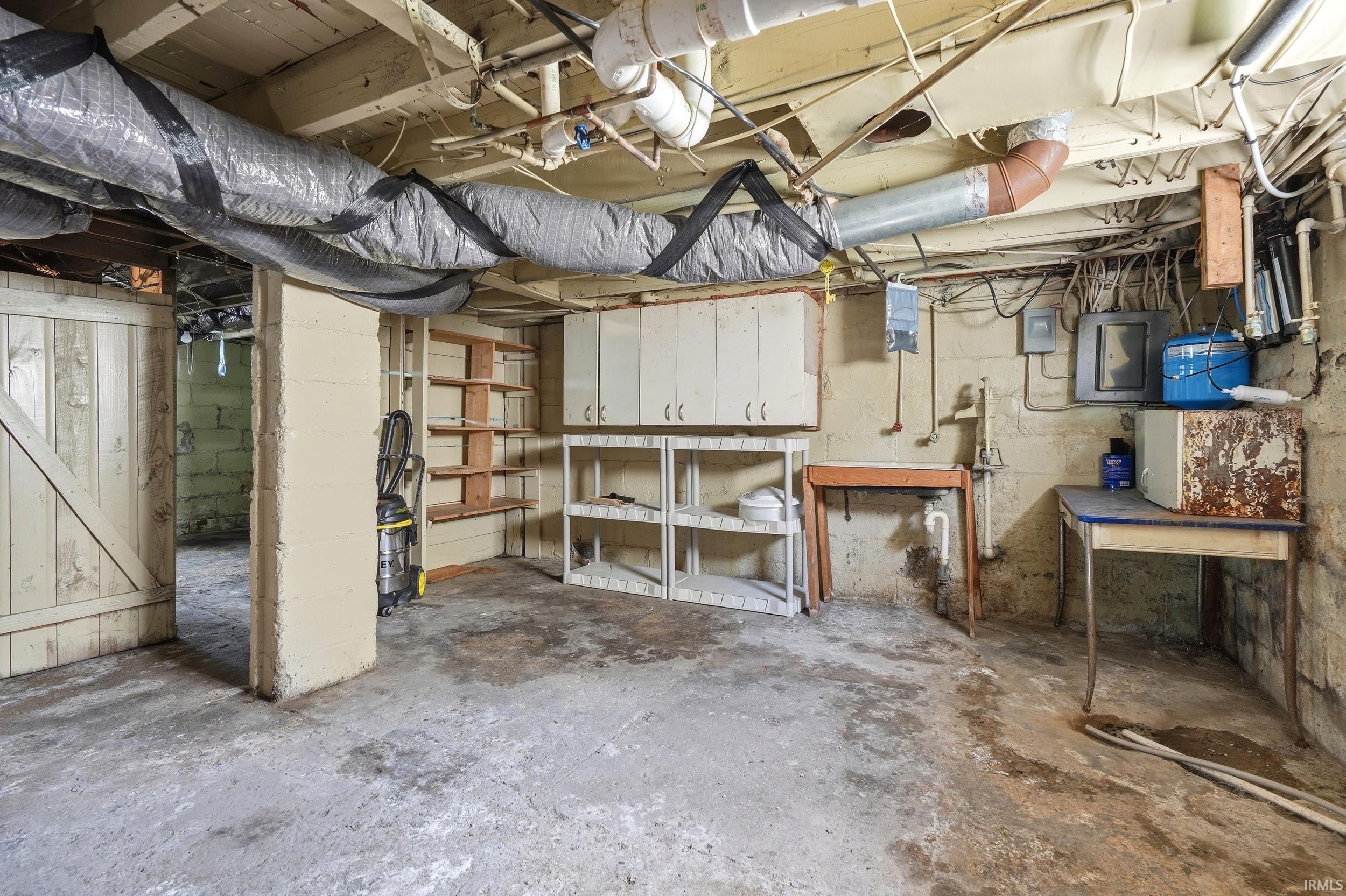 Unfinished basement space featuring exposed ceiling joists, concrete flooring, and an exposed block foundation