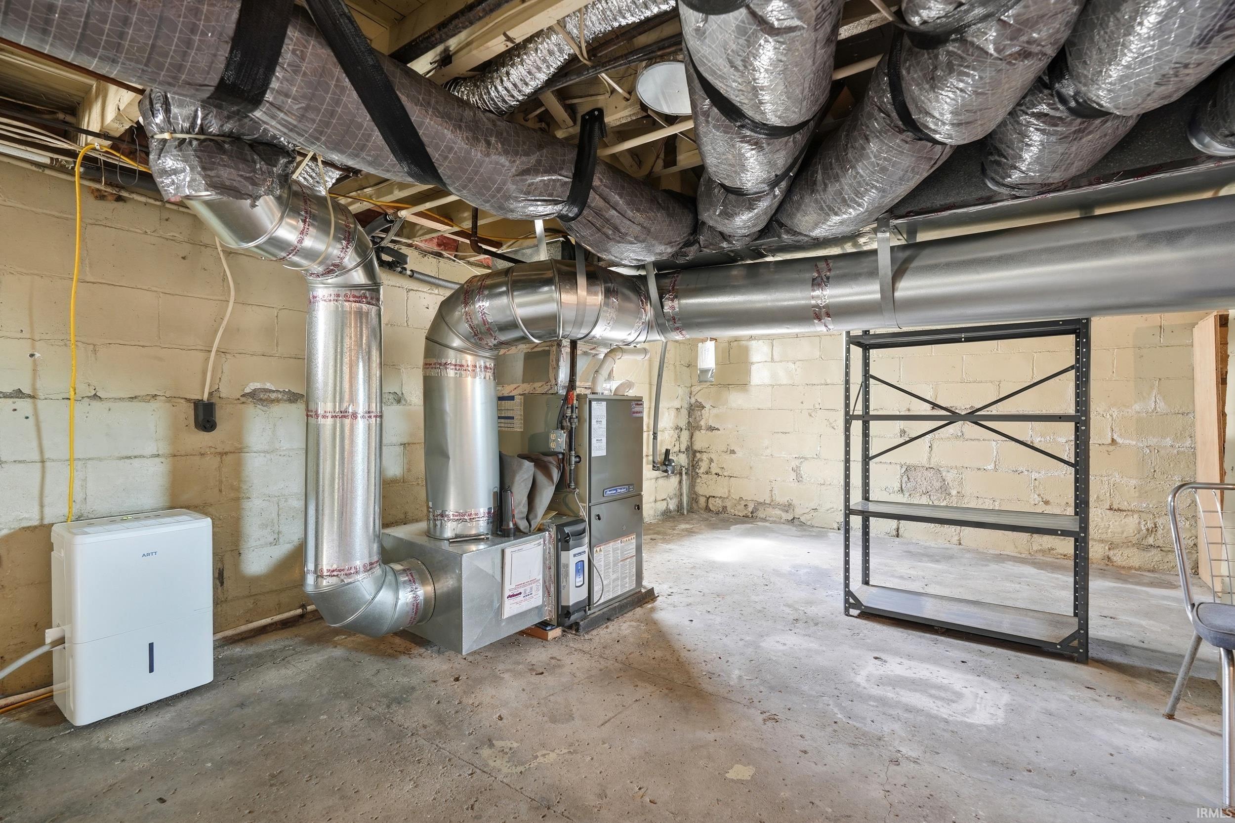 Basement utility area featuring exposed block walls, a concrete floor, and visible ductwork