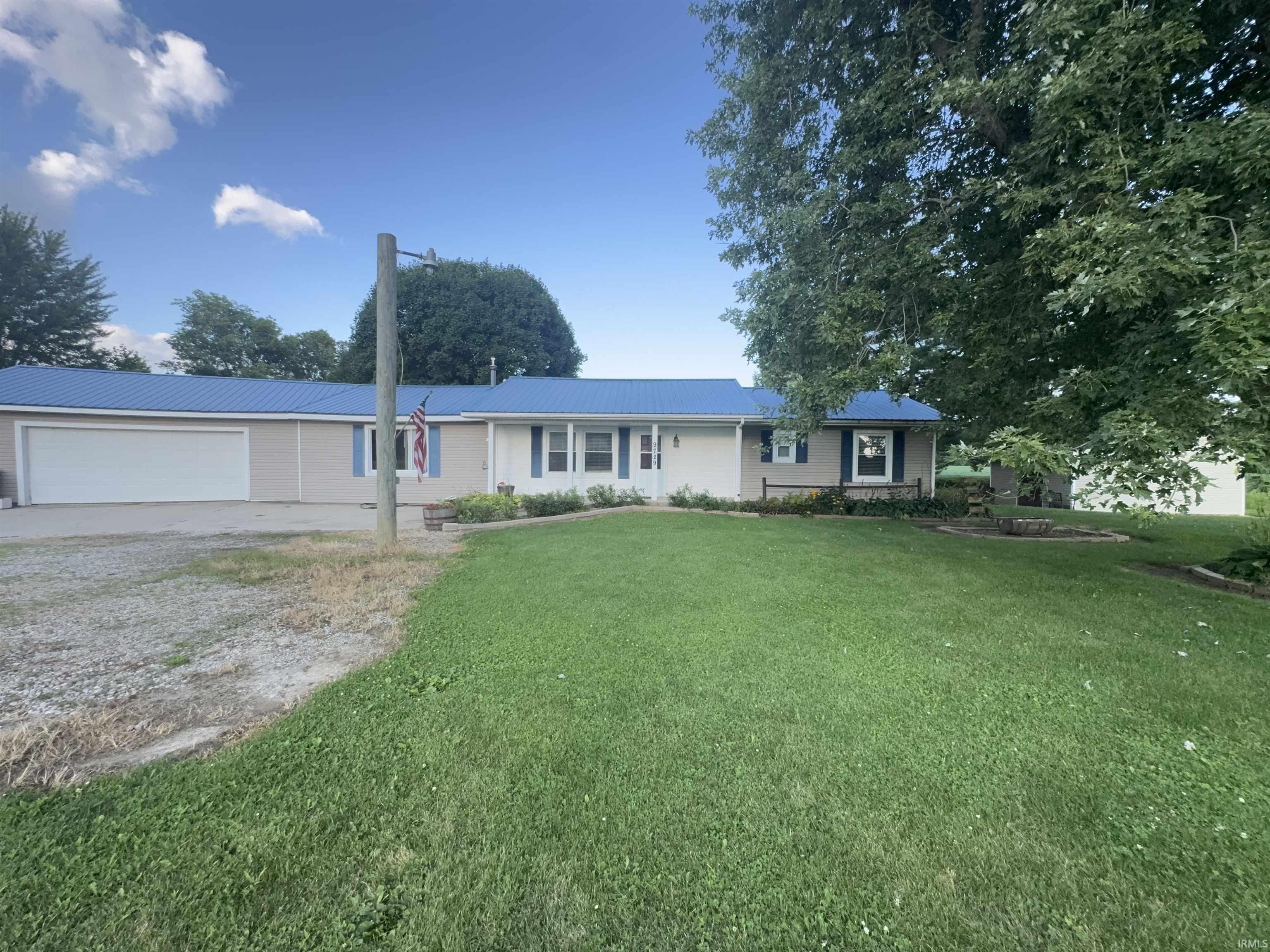 Charming ranch-style home set on expansive grounds featuring a manicured lawn, mature shade trees, and a two-car garage with attached carport