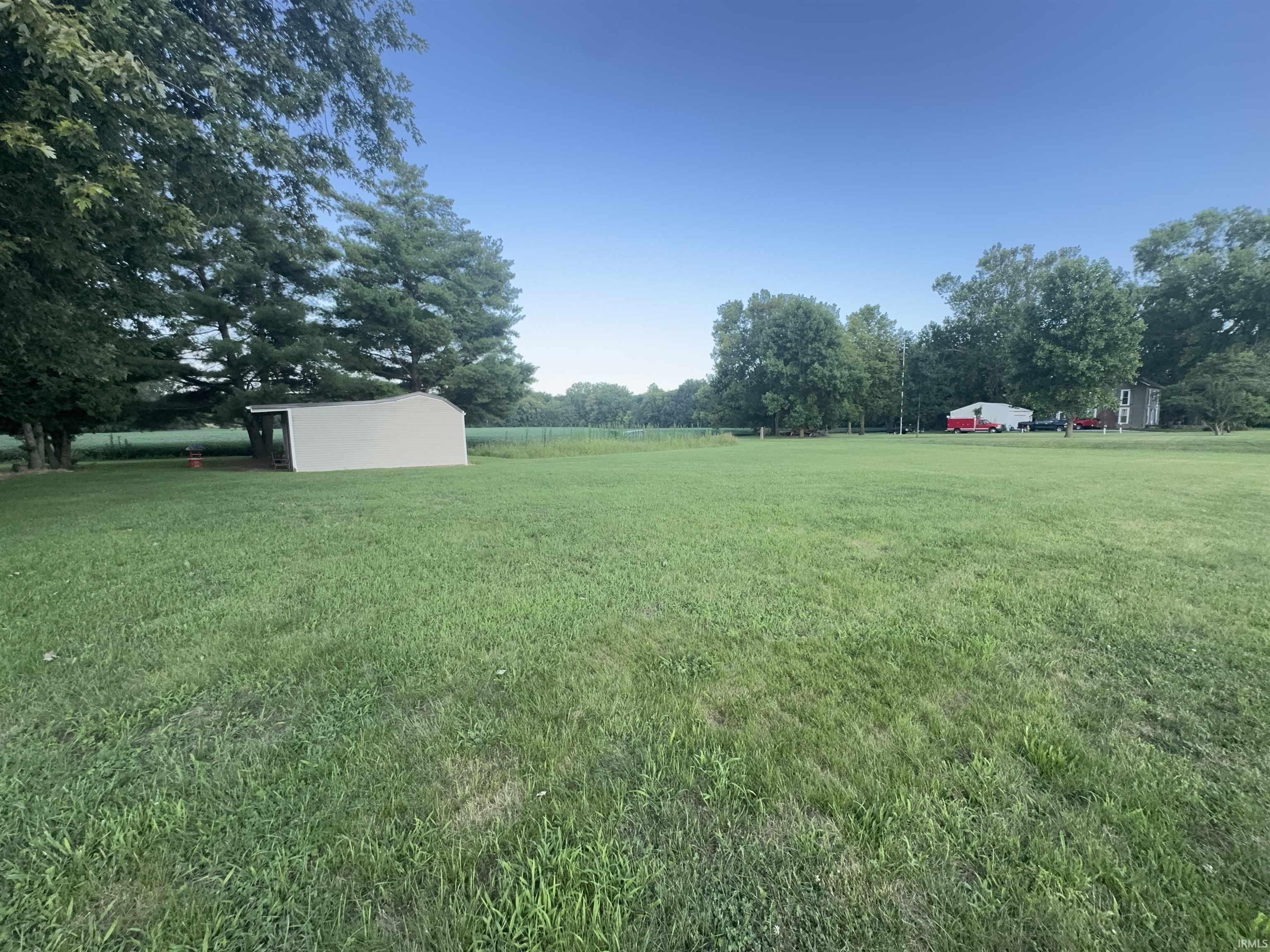 Expansive grounds featuring a manicured lawn with mature shade trees and established landscaping