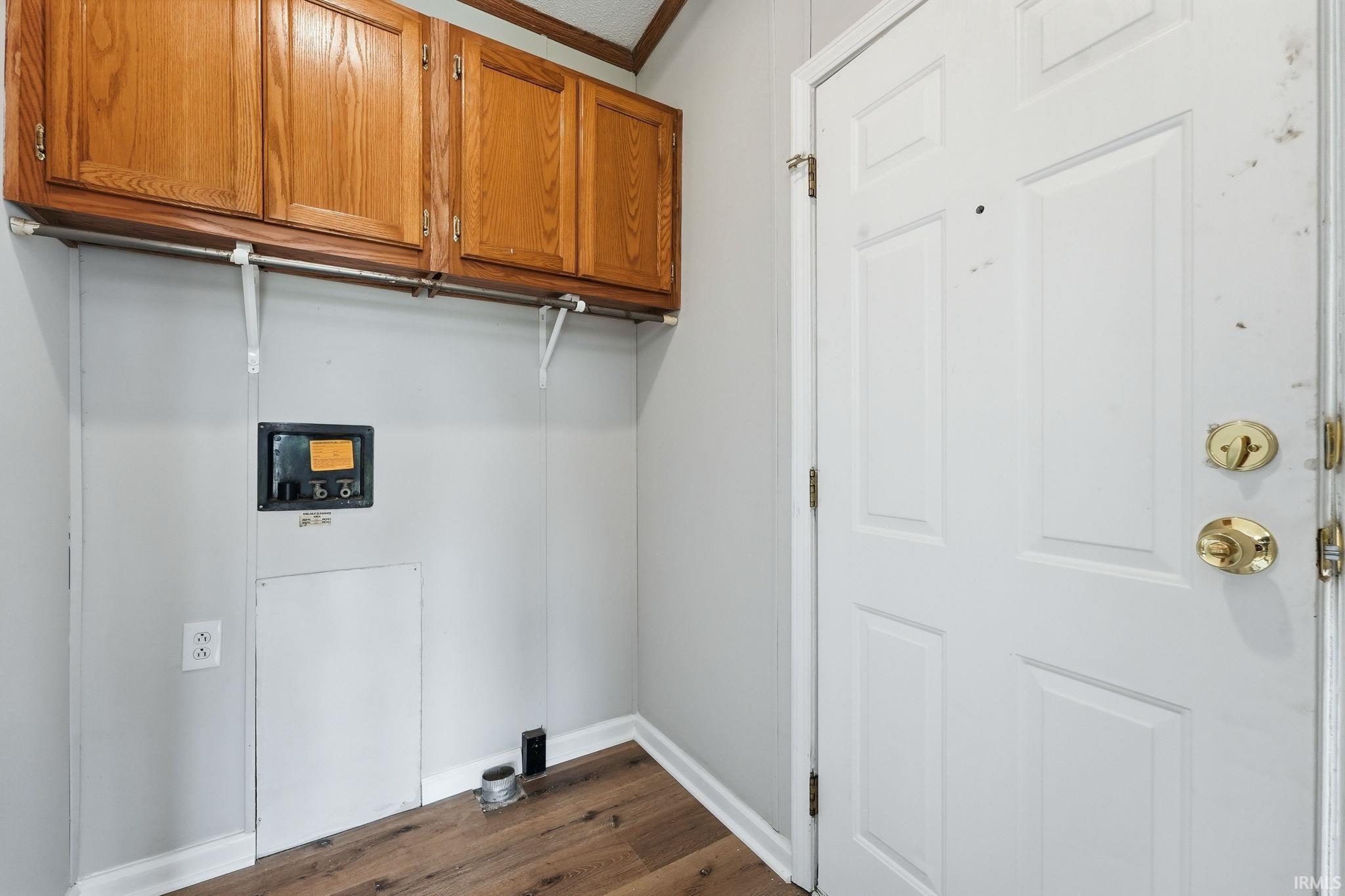 Dedicated utility space featuring wood-finish flooring, light gray walls, built-in wooden cabinetry, and a metal hanging rod