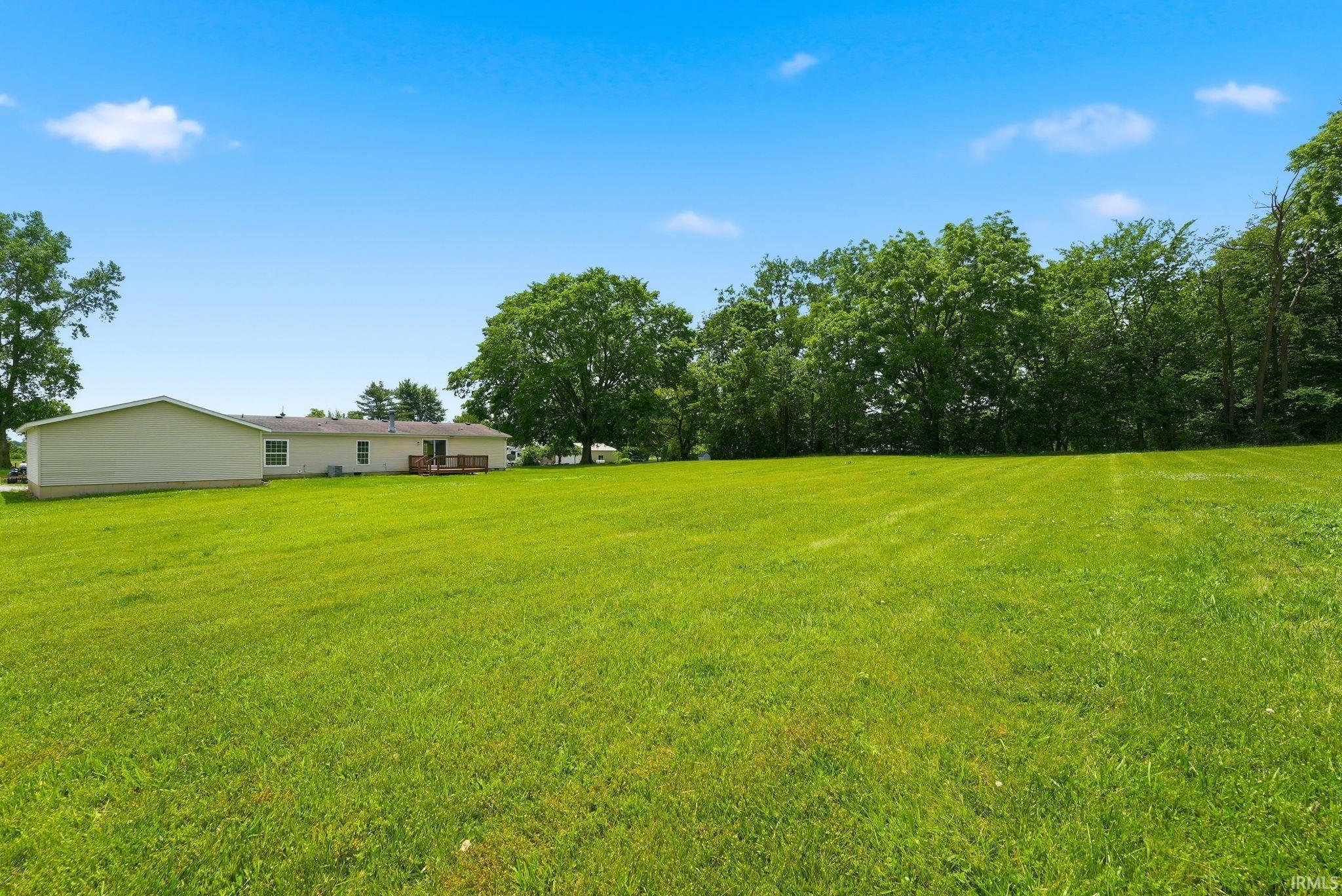 Expansive green lawn with a tree line providing natural screening