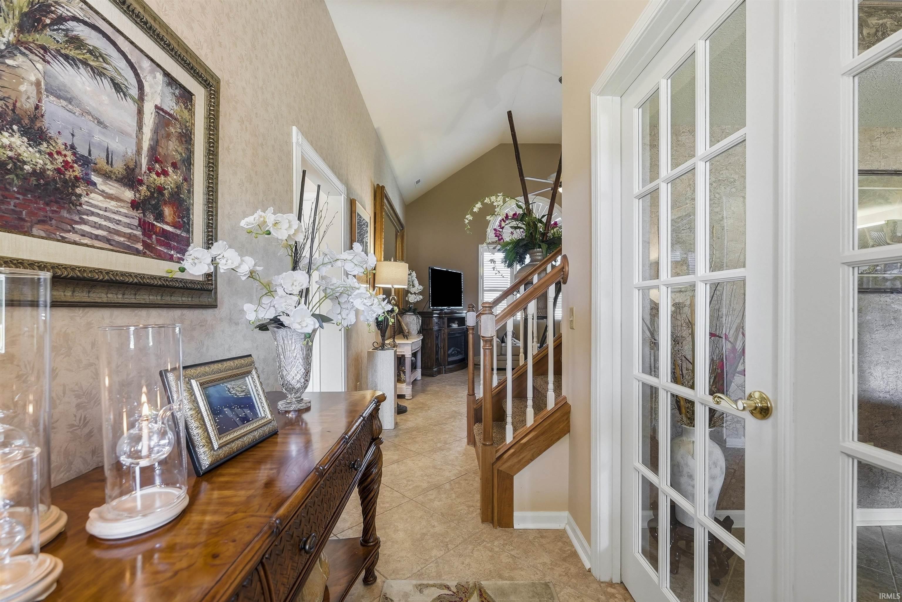 Foyer featuring tiled flooring, French doors, and a wood staircase with white balusters